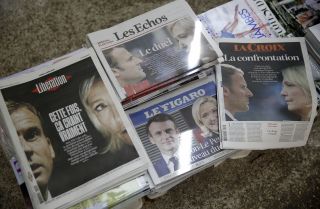 Photos of French President Emmanuel Macron and right-wing candidate Marine Le Pen are displayed on the front pages of French newspapers at a newsstand in Paris on April 11, 2022, after Macron and Le Pen won the most and second-most votes, respectively, in the first round of France's presidential election. 