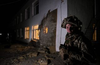 A Ukrainian soldier stands guard near debris after the reported shelling of a kindergarten in the settlement of Stanytsia Luhanska in eastern Ukraine on Feb. 17, 2022. 