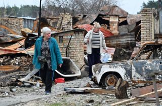Two women survey their destroyed houses in the Ukrainian village of Moshchun, northwest of Kyiv, on April 20, 2022.