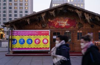 People wearing face masks walk past Christmas market stalls on Nov. 20, 2020, at Potsdamer Platz in Berlin, Germany.