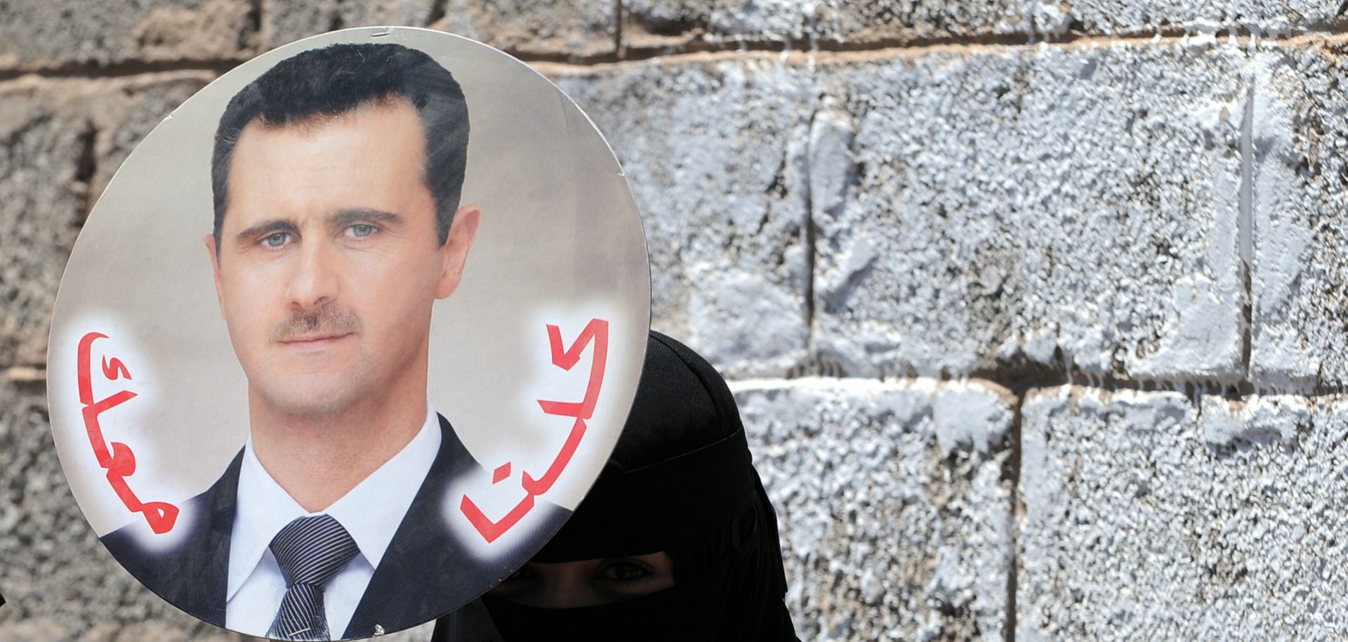 A Yemeni woman holds a photo of Syrian President Bashar al-Assad during a protest.