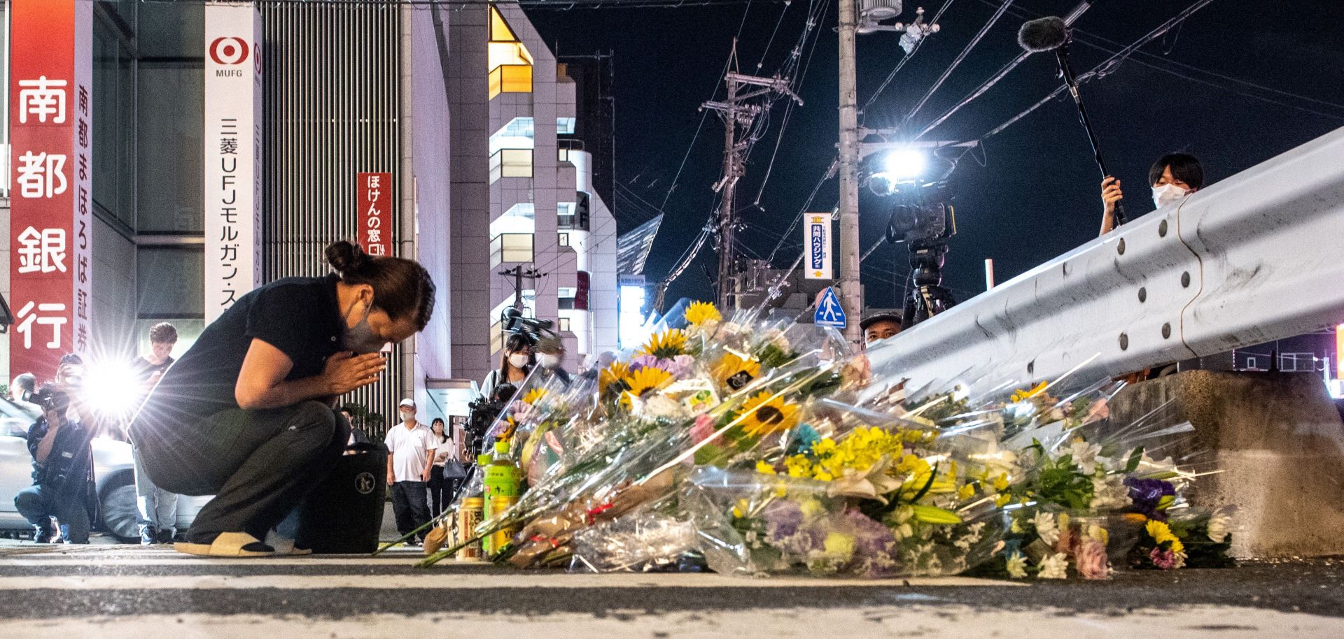 A woman mourns in front of a makeshift memorial outside the train station where former Japanese Prime Minister Shinzo Abe was shot and killed earlier in the day on July 8, 2022.