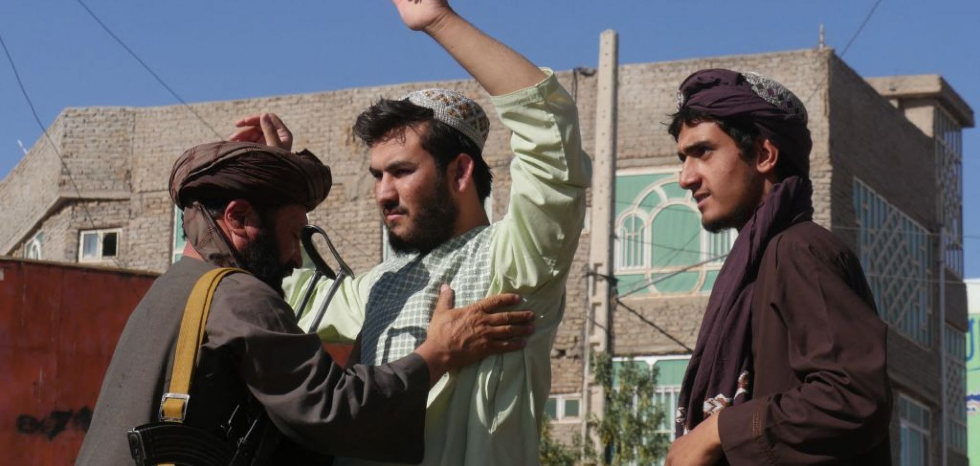 A Taliban fighter (L) frisks men at a checkpoint after a blast during Friday prayers Sept. 2, 2022, in Gazargah mosque in Herat.