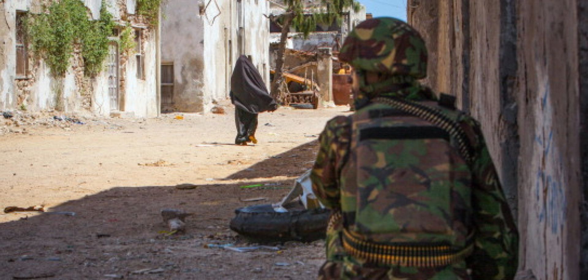 A soldier of the Kenyan Contingent serving with the African Union Mission in Somalia (AMISOM) keeps watch on a street in the center of the southern Somali port city of Kismayo on October 5, 2012. Meanwhile, a combat engineering team inspects the surrounding area following reports of a suspected improvised explosive device (IED) left behind by the Al-Qaeda-affiliated extremist group Al Shabaab. 