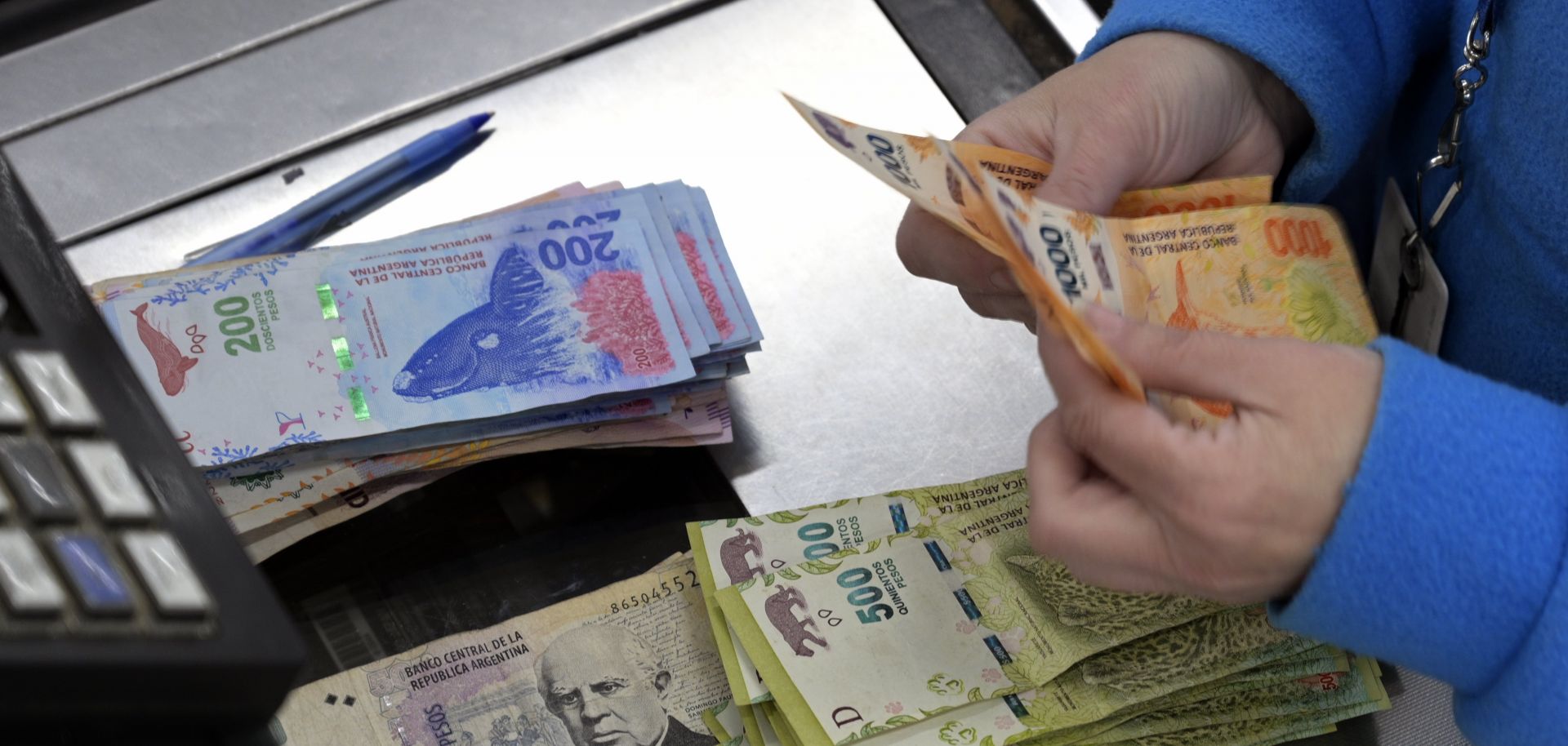 A supermarket cashier counts Argentine pesos in Buenos Aires on Aug. 15, 2019.
