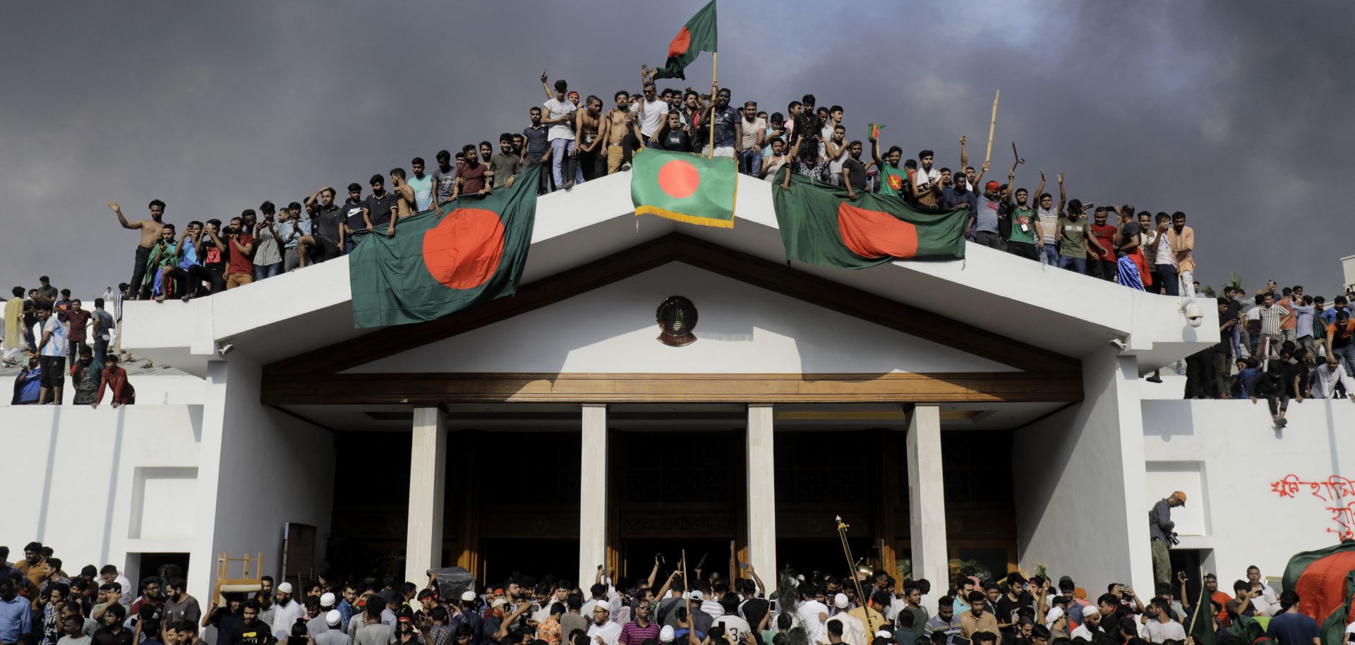 Anti-government protesters display Bangladesh's national flag as they storm Prime Minister Sheikh Hasina's palace in Dhaka on Aug. 5, 2024.