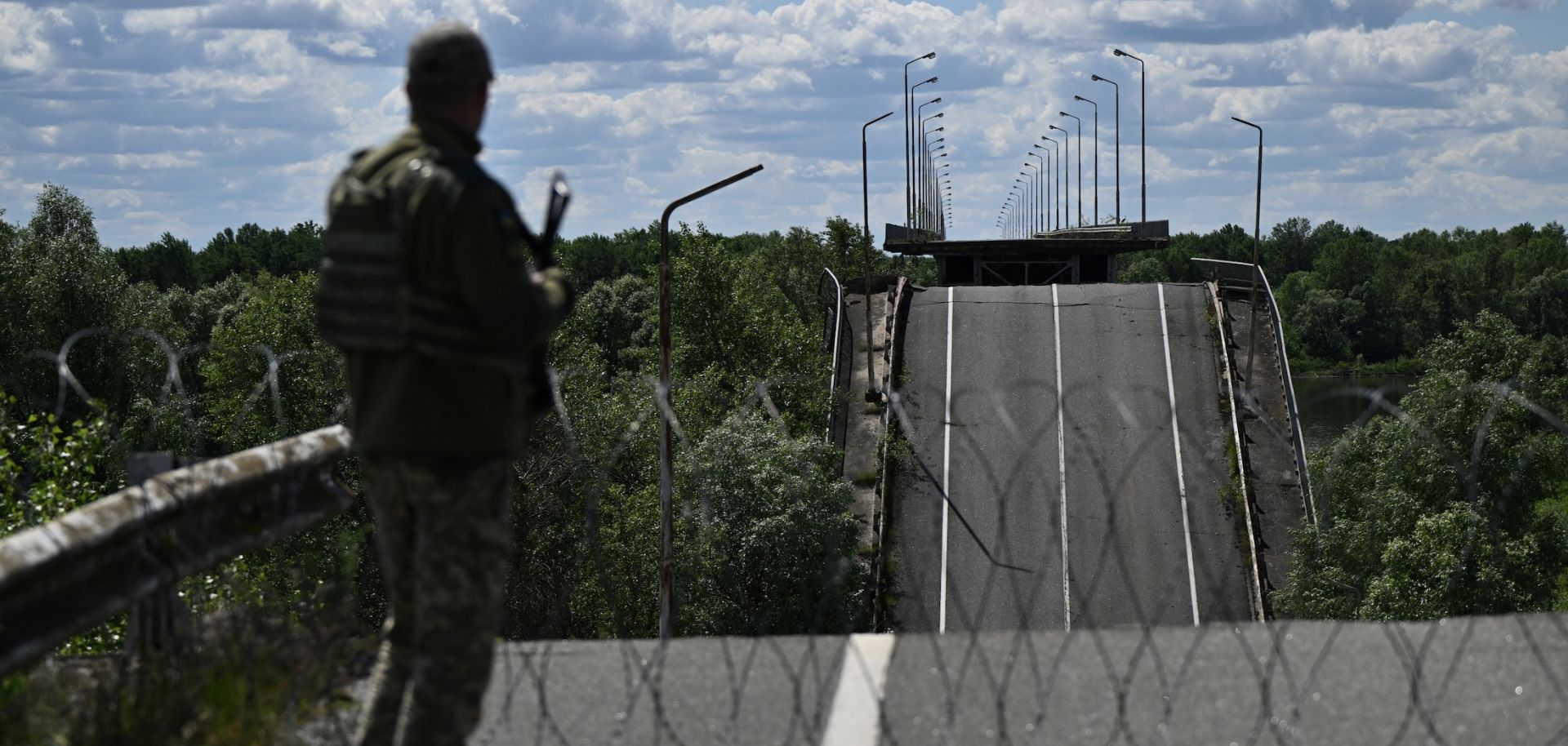 An officer of the State Border Guard Service of Ukraine stands on a destroyed bridge over the Dnipro River, which forms the state border between Ukraine and Belarus, on June 1, 2026.