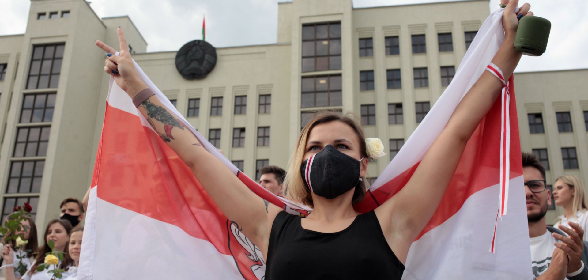 A woman wearing a face mask holds the former flag of Belarus at an anti-government protest in Minsk on Aug. 14, 2020. 