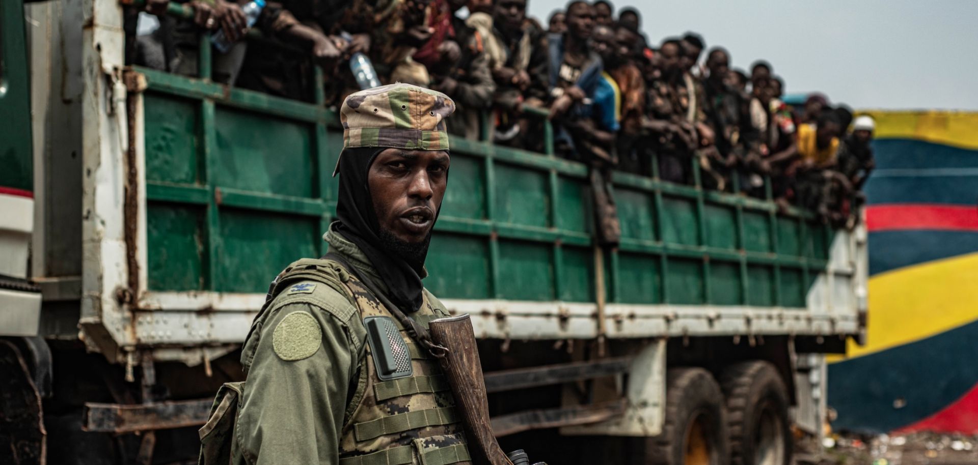 An M23 fighter stands in the foreground as detained Congolese soldiers are loaded onto trucks on Jan. 30, 2025, in Goma, Democratic Republic of Congo. 