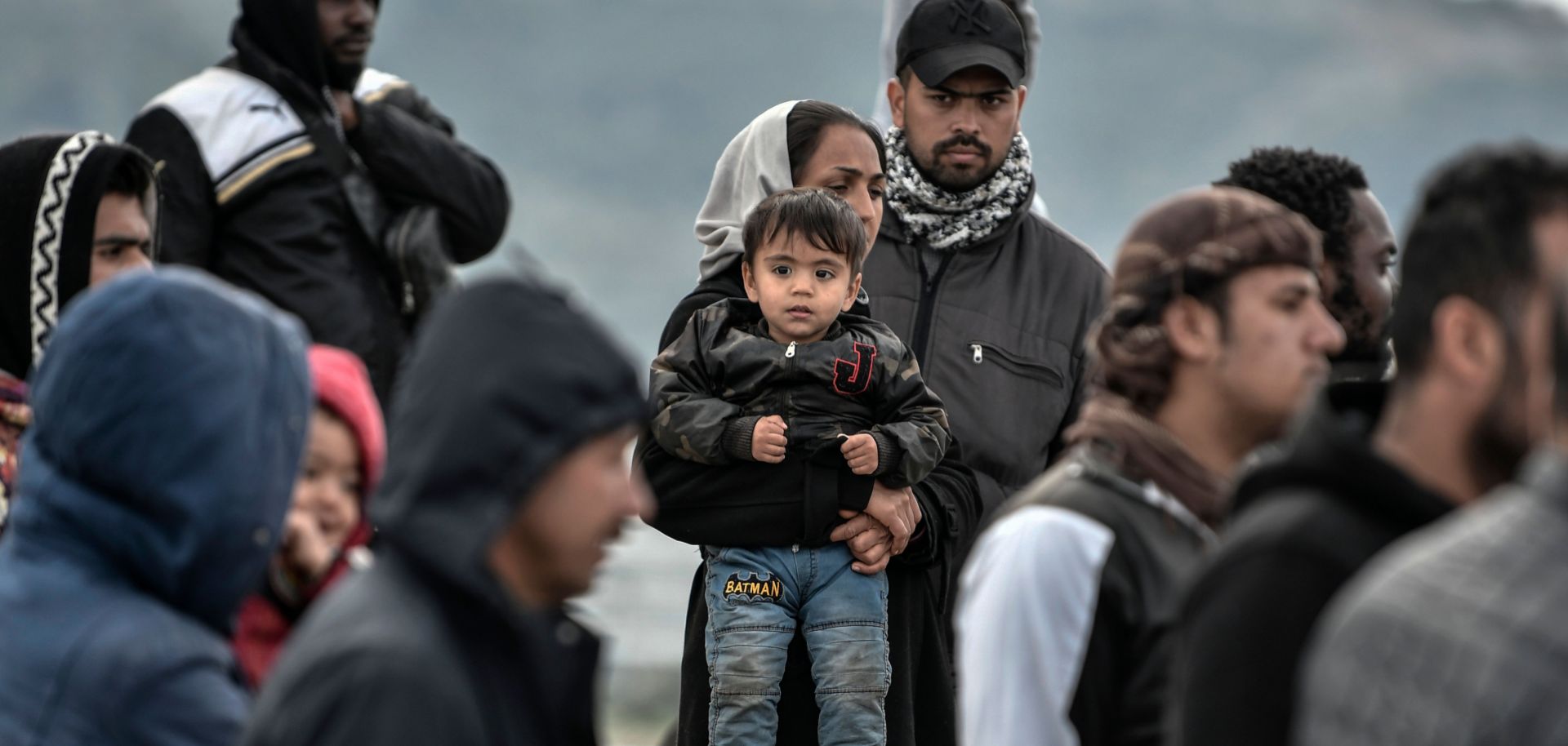 Refugees and migrants stand at a port upon arriving at the Greek island of Lesbos on March 7, 2020.
