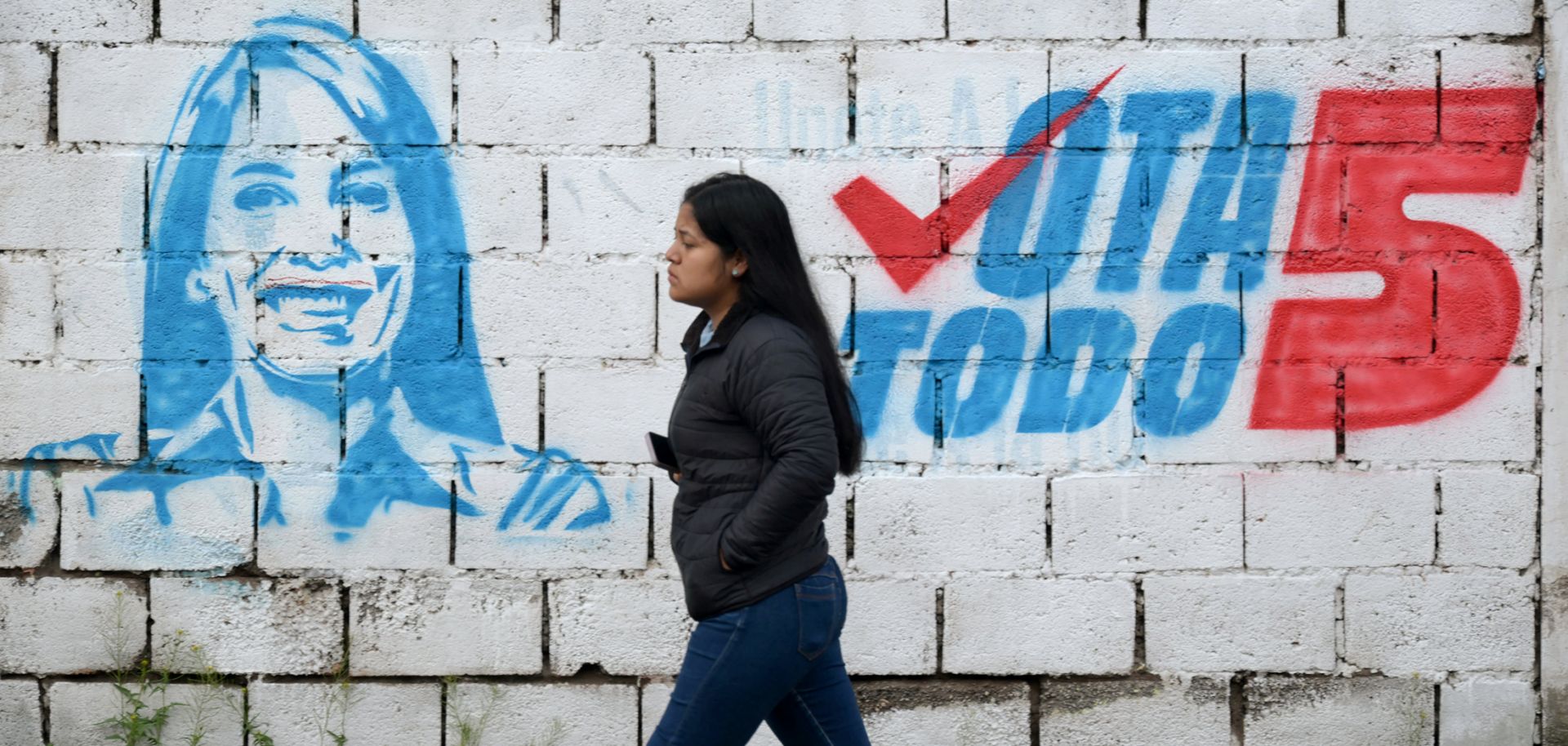 A woman walks past a mural of leftist presidential candidate Luisa Gonzalez in Quito, Ecuador, on Feb. 5, 2025.