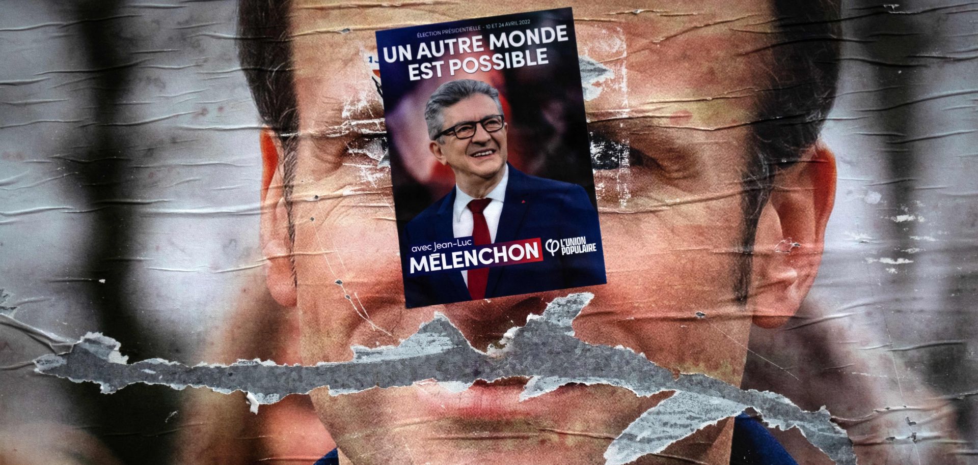 A campaign flyer reading "another world is possible" in support of far-left presidential candidate Jean-Luc Melenchon covers a vandalized poster of French President Emmanuel Macron in Paris, France, on April 19, 2022. Melechon came in third place behind Macron and right-wing candidate Marine Le Pen in the first round of France’s presidential election on April 10.