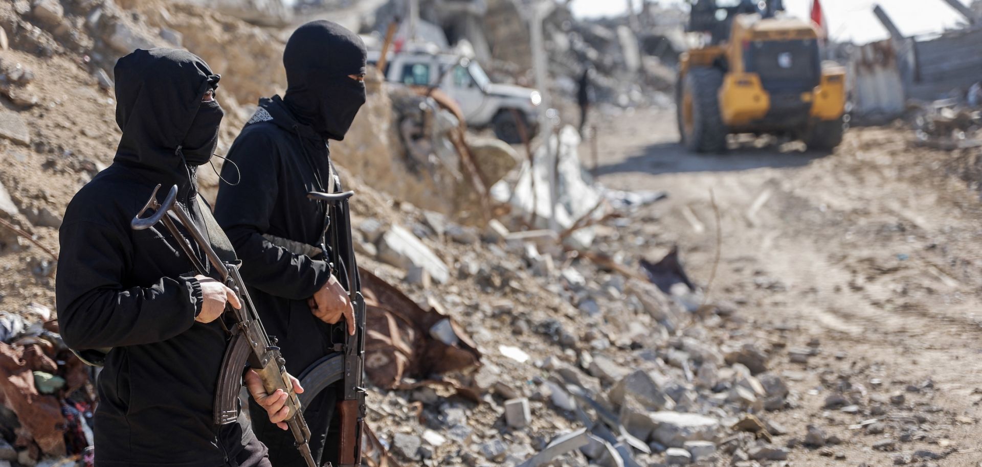 Palestinian Hamas militants stand guard as Egyptian and Red Cross workers search for the bodies of the last two remaining hostages from under the rubble of the Jabalia refugee camp, in the northern Gaza Strip, on Dec. 1, 2025.