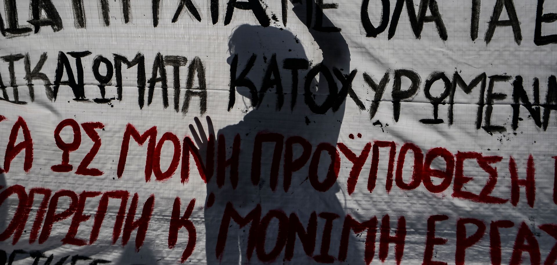 A student silhouette is seen behind a banner as he takes part in a rally in central Athens.