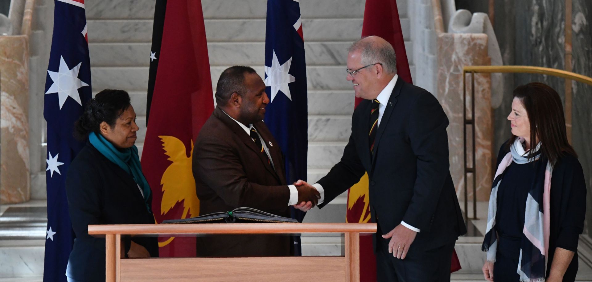 Papua New Guinea's Prime Minister James Marape (left) shakes hands with Australia's Prime Minister Scott Morrison as their wives look on in Canberra during July.