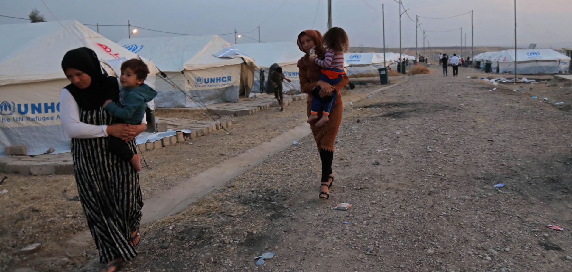 Syrian refugees walk outside a tent at a camp near the Iraqi Kurdish town of Bardarash on Oct. 18, 2019.