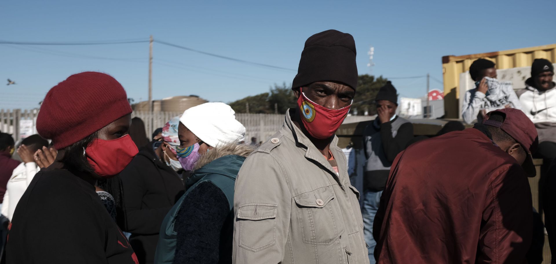 People stand in line to receive grant payments from the South African Social Security Agency (SASSA) in Khayelitsha, a township located near Cape Town, on May 4, 2020. 