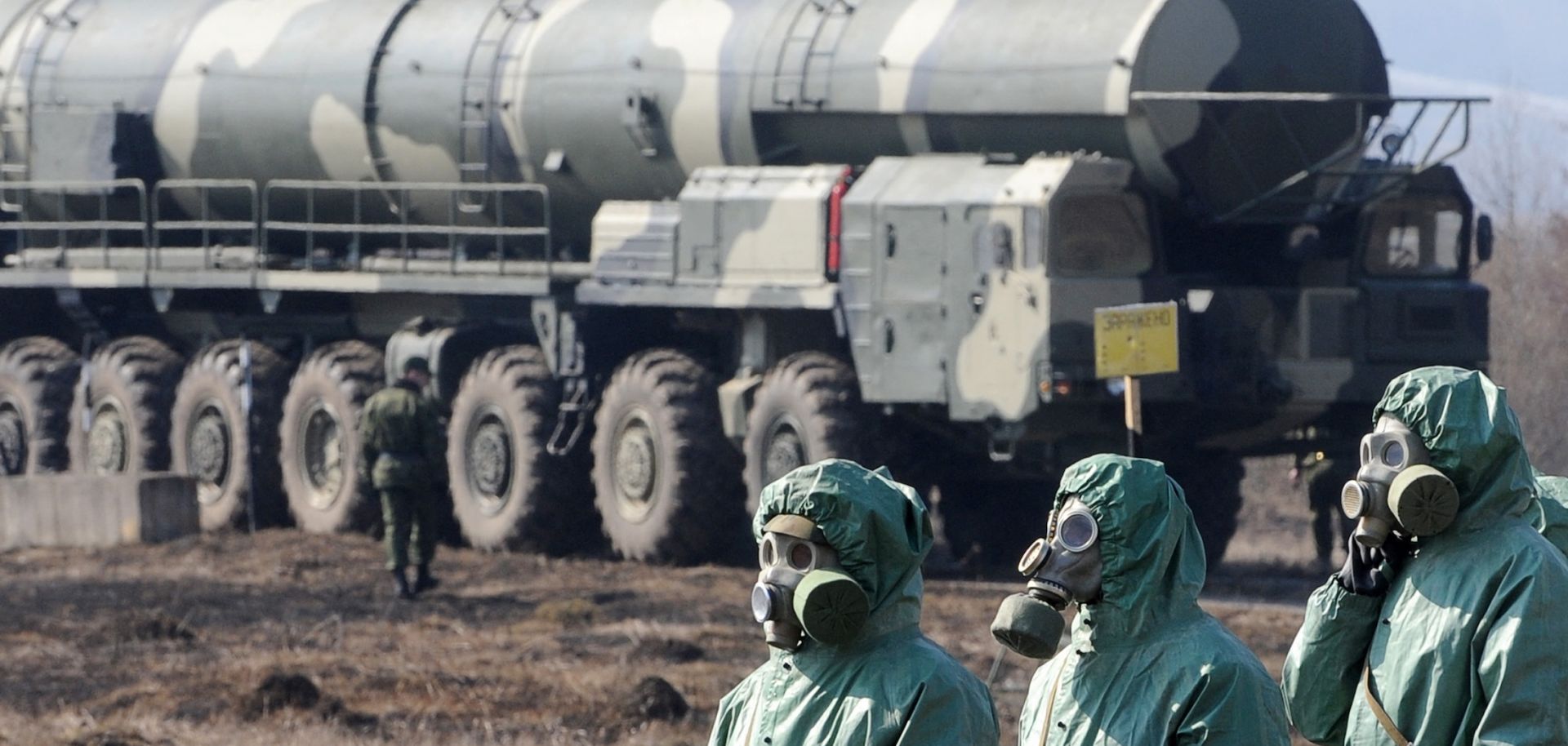 Russian soldiers wear chemical protection suits as they stand next to a military fueler on the base of a prime mover of Russian Topol intercontinental ballistic missile during a training session at the Serpukhov's military missile forces research institute some 100km outside Moscow on April 6, 2010.