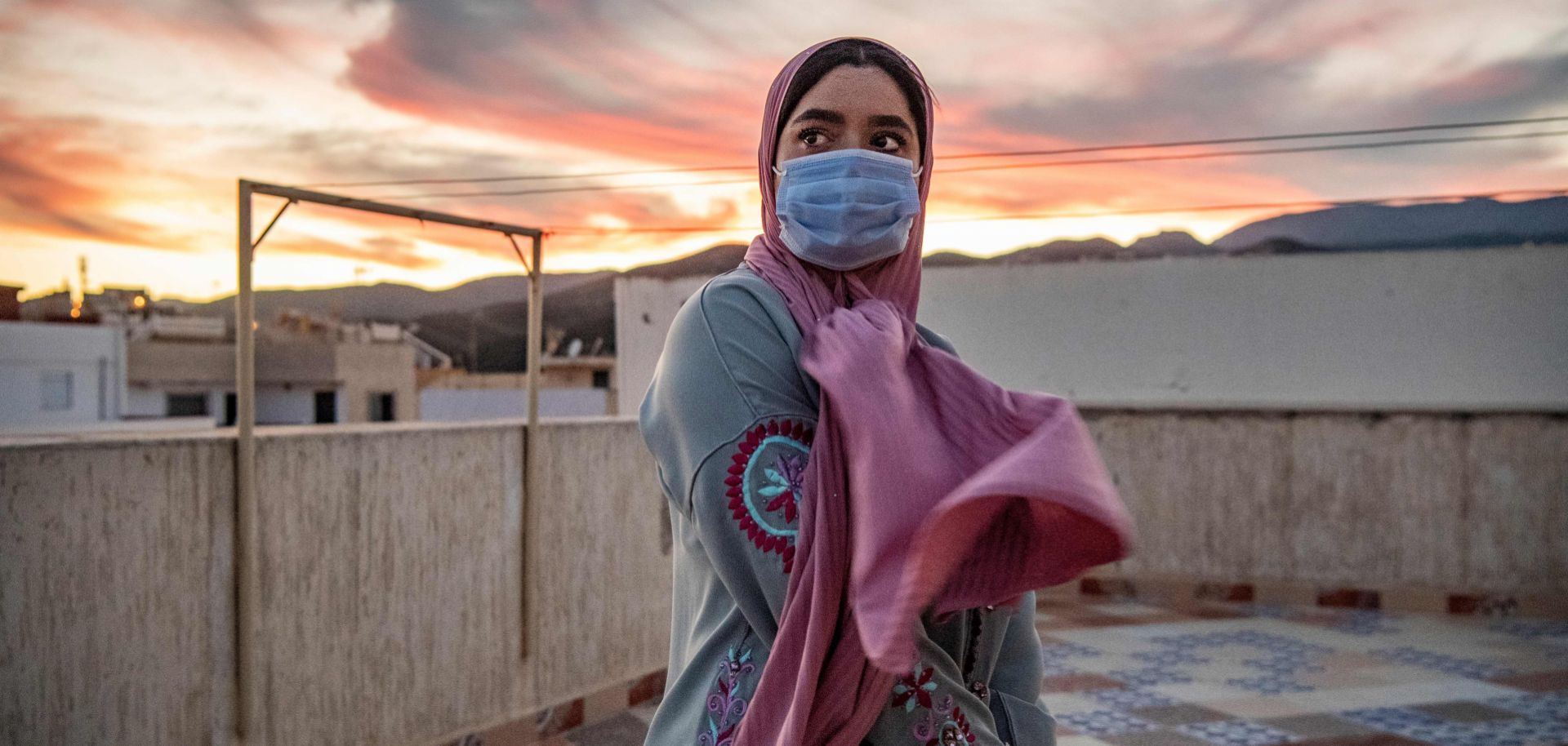 A woman wearing a face mask stands at a terrace on top of a building in Fnideq, Morocco, on Aug. 28, 2020.