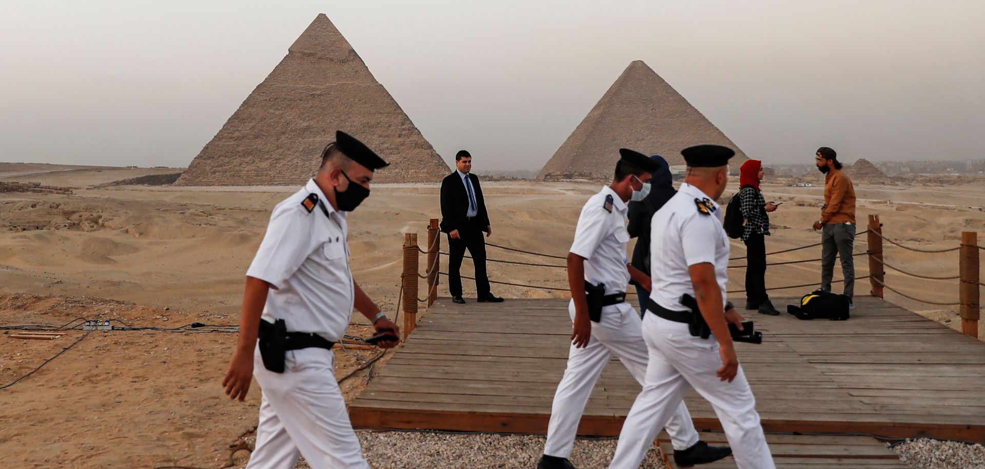 Policemen walk near an overlook at the Giza Pyramids in Egypt ahead of a ceremony commemorating the launch of the site's first environmentally-friendly bus and restaurant on Oct. 20, 2020. 