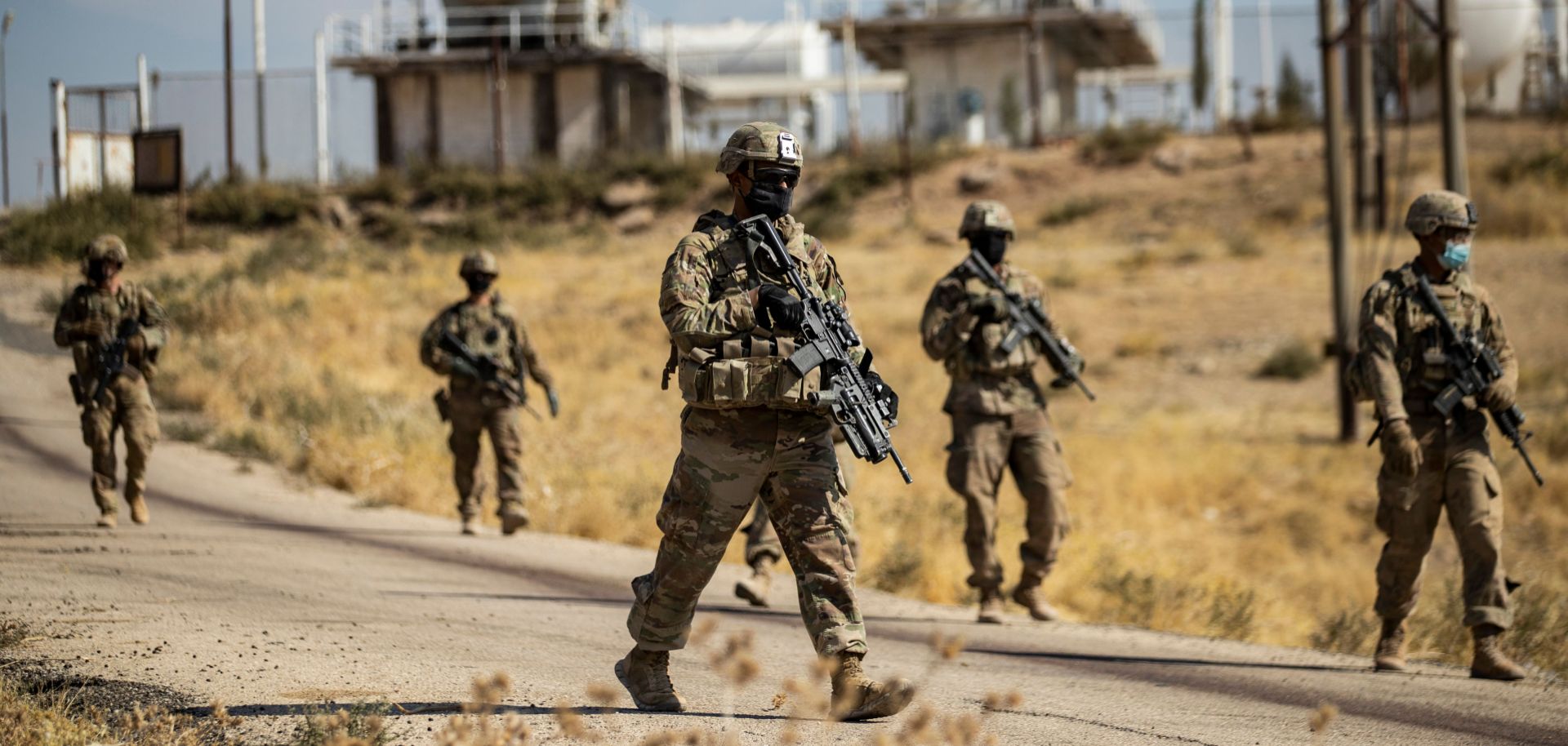 U.S. soldiers walk during a military patrol near an oil production facility in the countryside of northeastern Syria on Oct. 27, 2020. 
