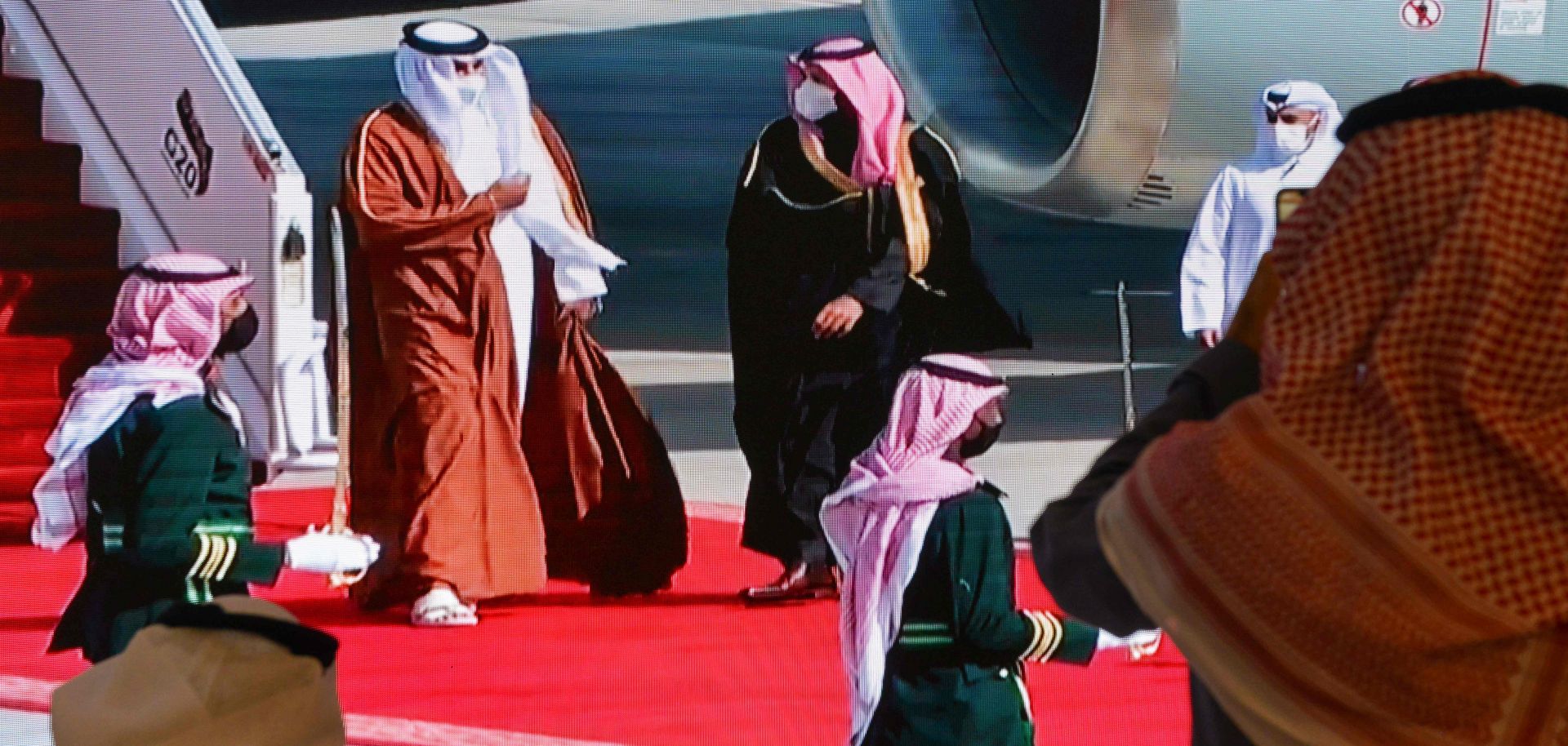 Journalists watch Saudi Crown Prince Mohammed bin Salman (center right) welcome Qatar’s Sheikh Tamim bin Hamad Al Thani (center left) on a screen ahead of the Gulf Cooperation Council (GCC) summit in the Saudi city of al-Ula on Jan. 5, 2021. 