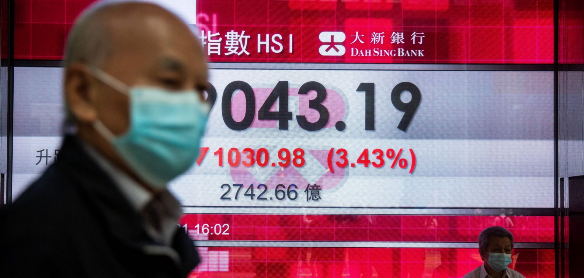 People walk past an electronic display showing Hong Kong’s Hang Seng Index in the city’s central district on Feb. 26, 2021.