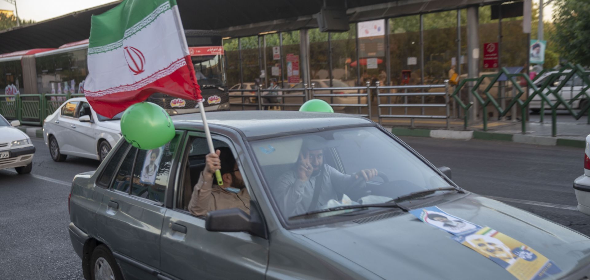 Supporters of Iranian presidential candidate Ebrahim Raisi hold an Iranian flag out of a car window on a street in Tehran on June 11, 2021. 