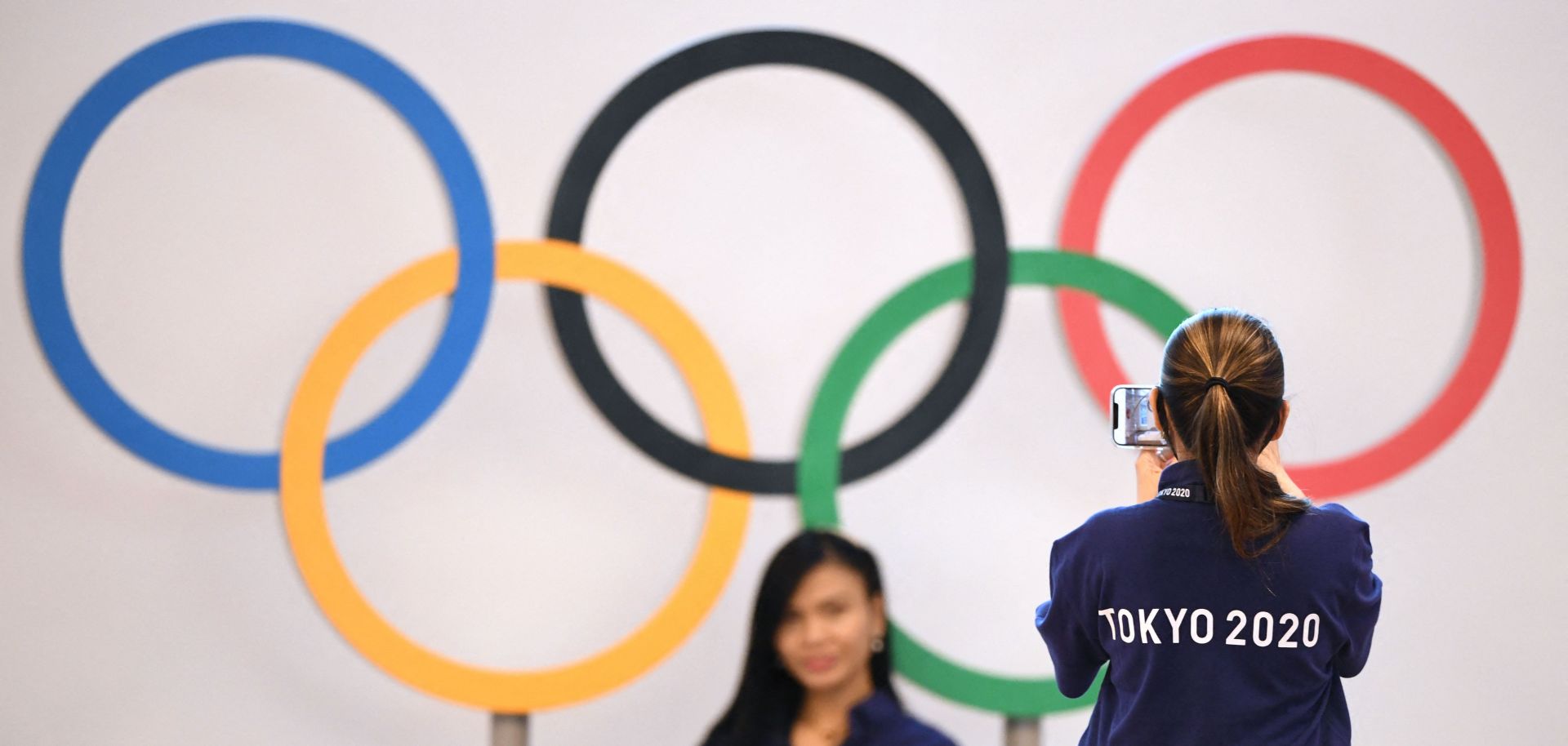 Workers take a picture in front of the Olympic rings at the international airport in Tokyo, Japan, on July 15, 2021.