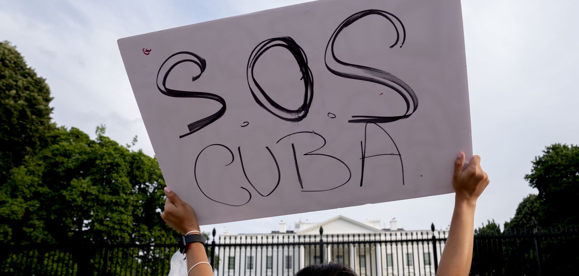 A demonstrator holds up a sign in solidarity with protesters in Cuba outside the White House on July 18, 2021. 