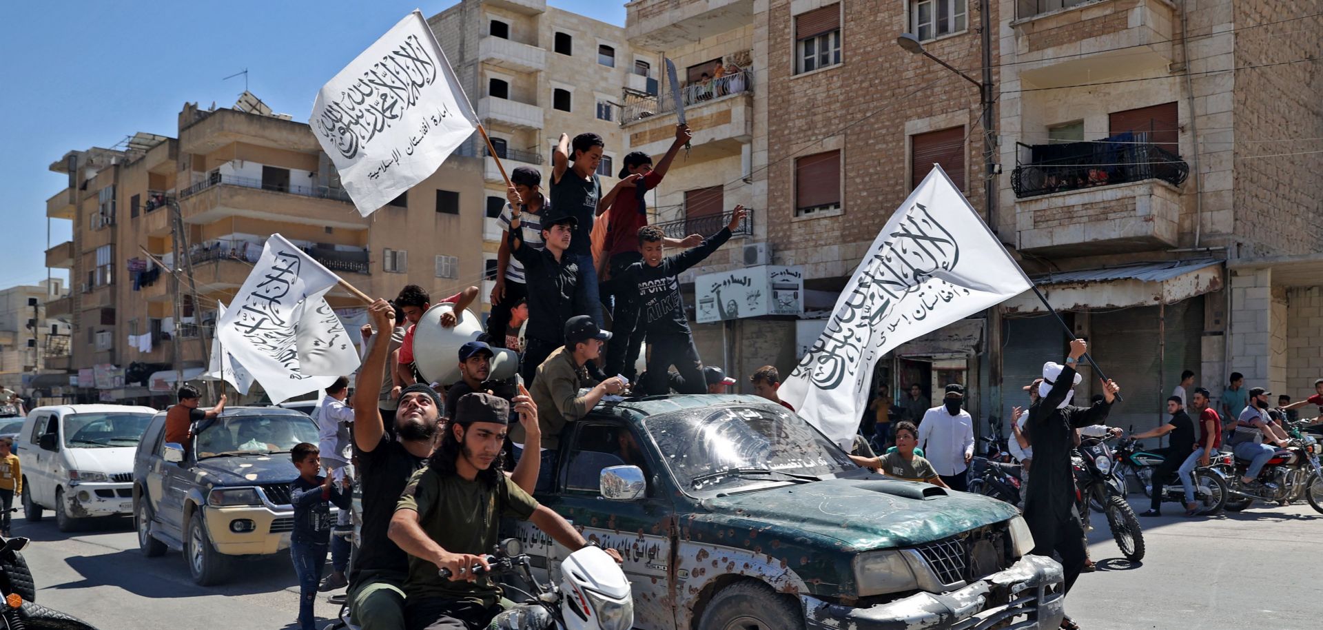 Members of Syria's top jihadist group, the al Quada-linked Hayat Tahrir al-Sham, parade through the city of Idlib on Aug. 20, 2021, in celebration of the Taliban's takeover of Afghanistan.