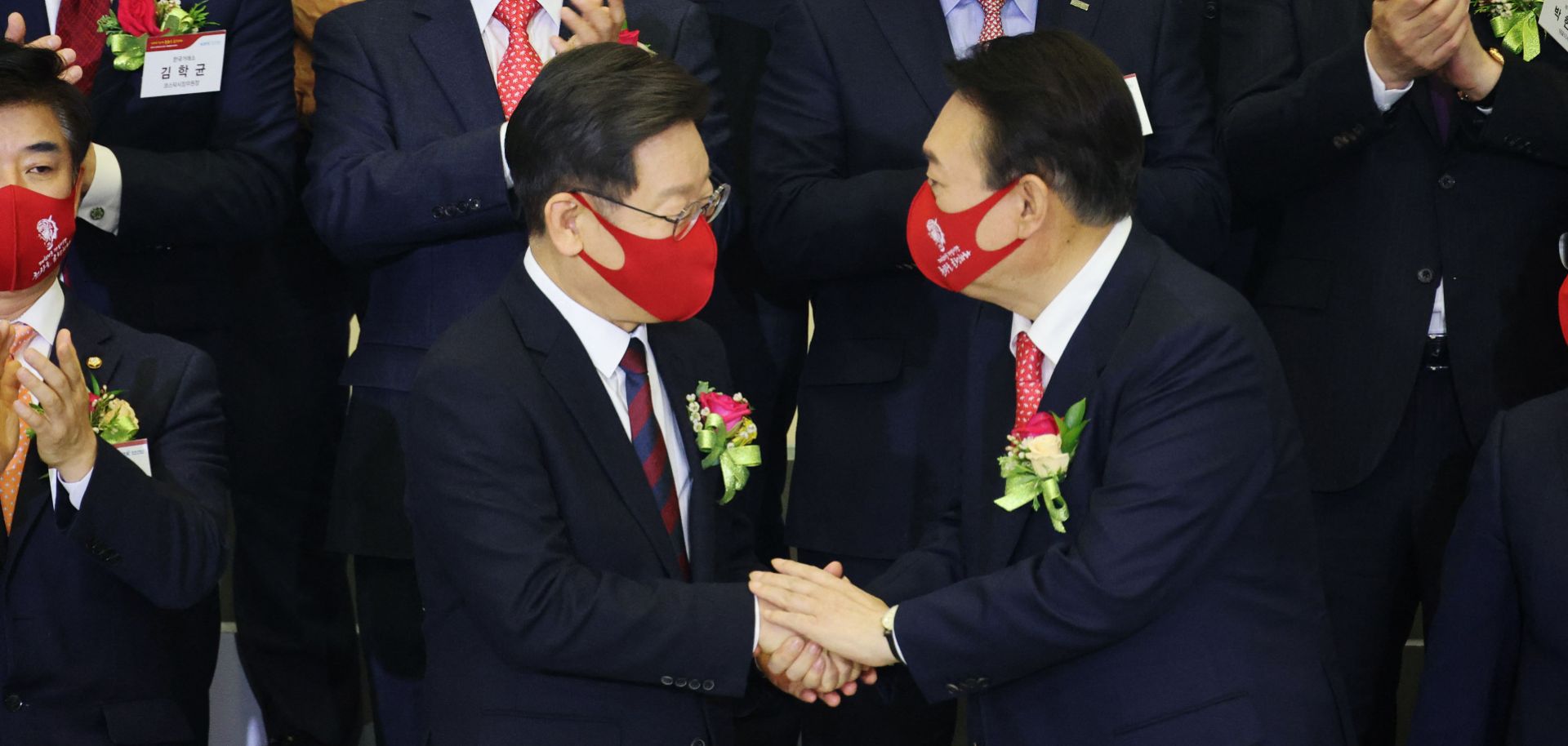 Yoon Suk Yeol (front right), the presidential candidate for South Korea's main opposition party, shakes hands with the ruling party’s candidate, Lee Jae-myung, in Seoul on Jan. 3, 2022. 