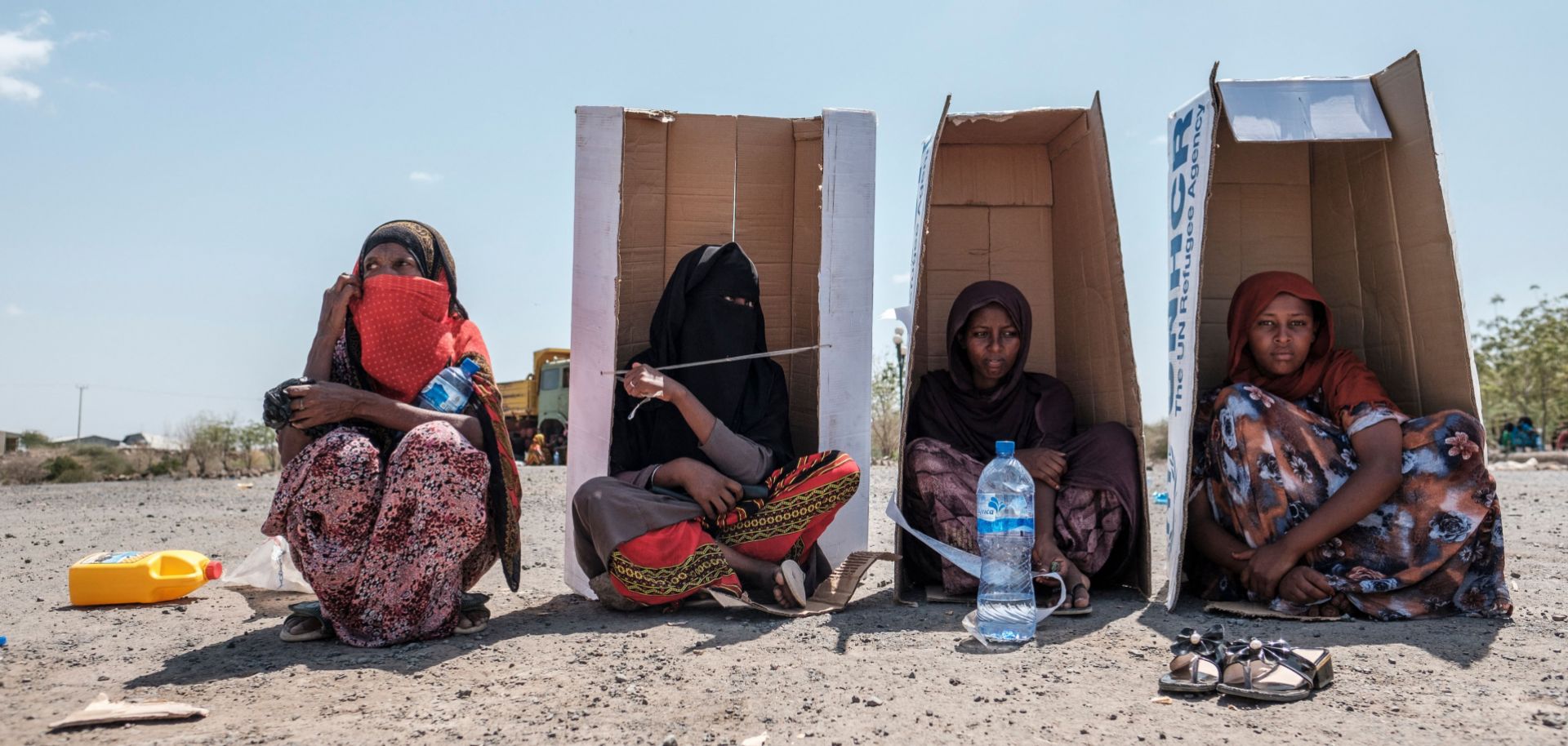 Women sit under U.N.-branded cardboard boxes in Semera, Ethiopia, on Feb. 14, 2022, as they wait to be registered by the authorities at a hotel compound hosting civilians fleeing violence. 