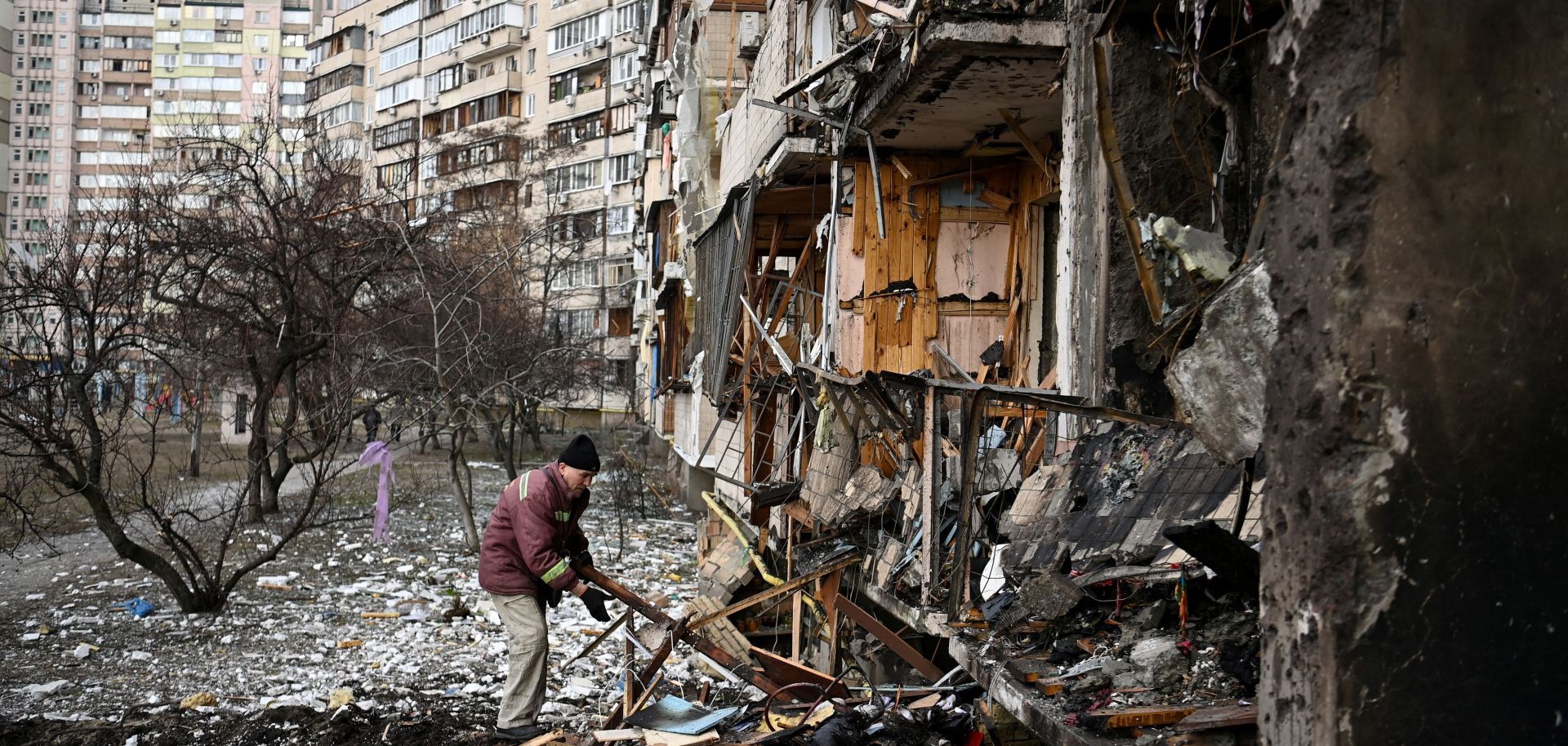 A man clears debris around a residential building allegedly hit by a military shell in a suburb outside of Kyiv, Ukraine, on Feb. 25, 2022.