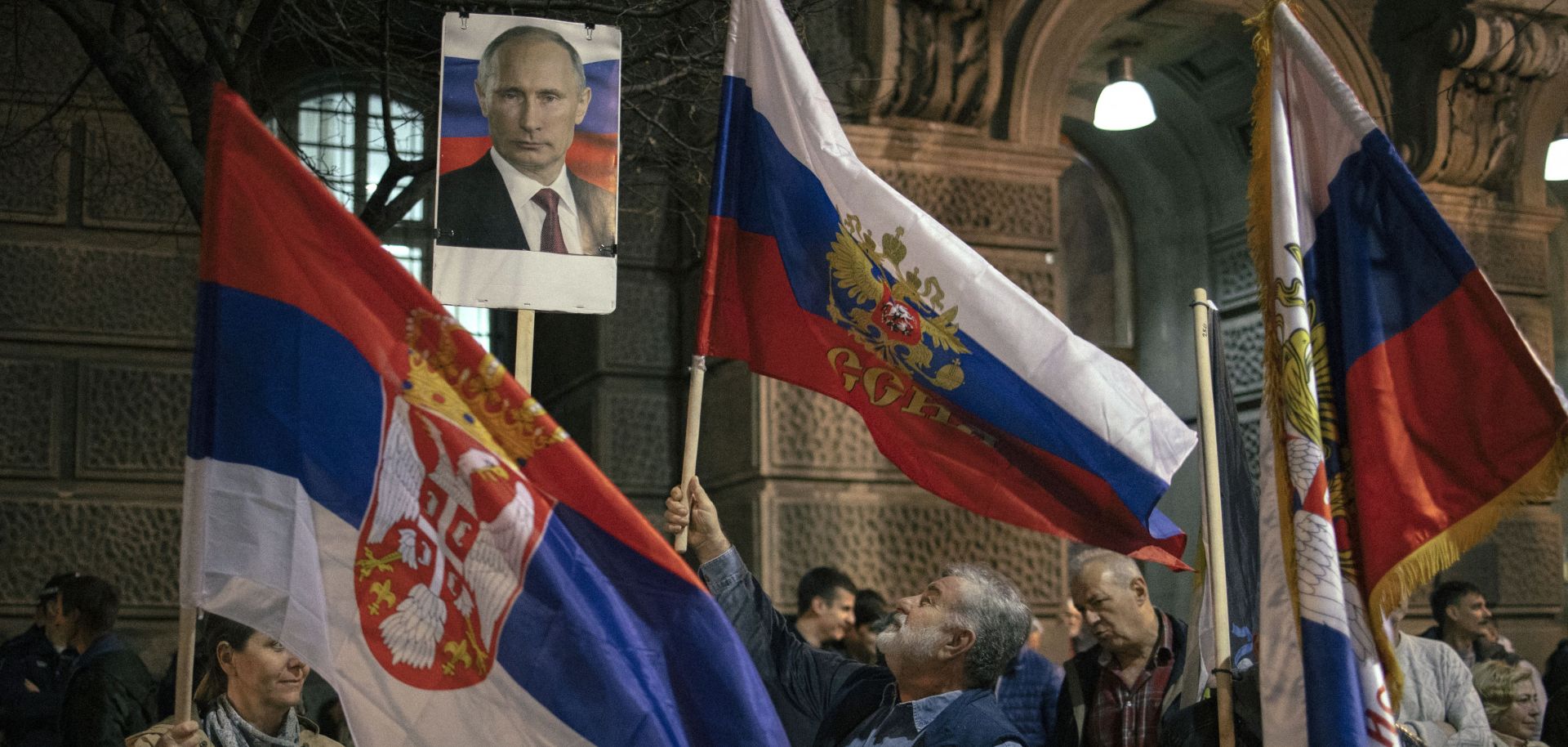 Demonstrators in Belgrade, Serbia, hold up Serbian flags and a photo of Russian President Vladimir Putin on March 24, 2022, during a rally in support of the Russian invasion of Ukraine.