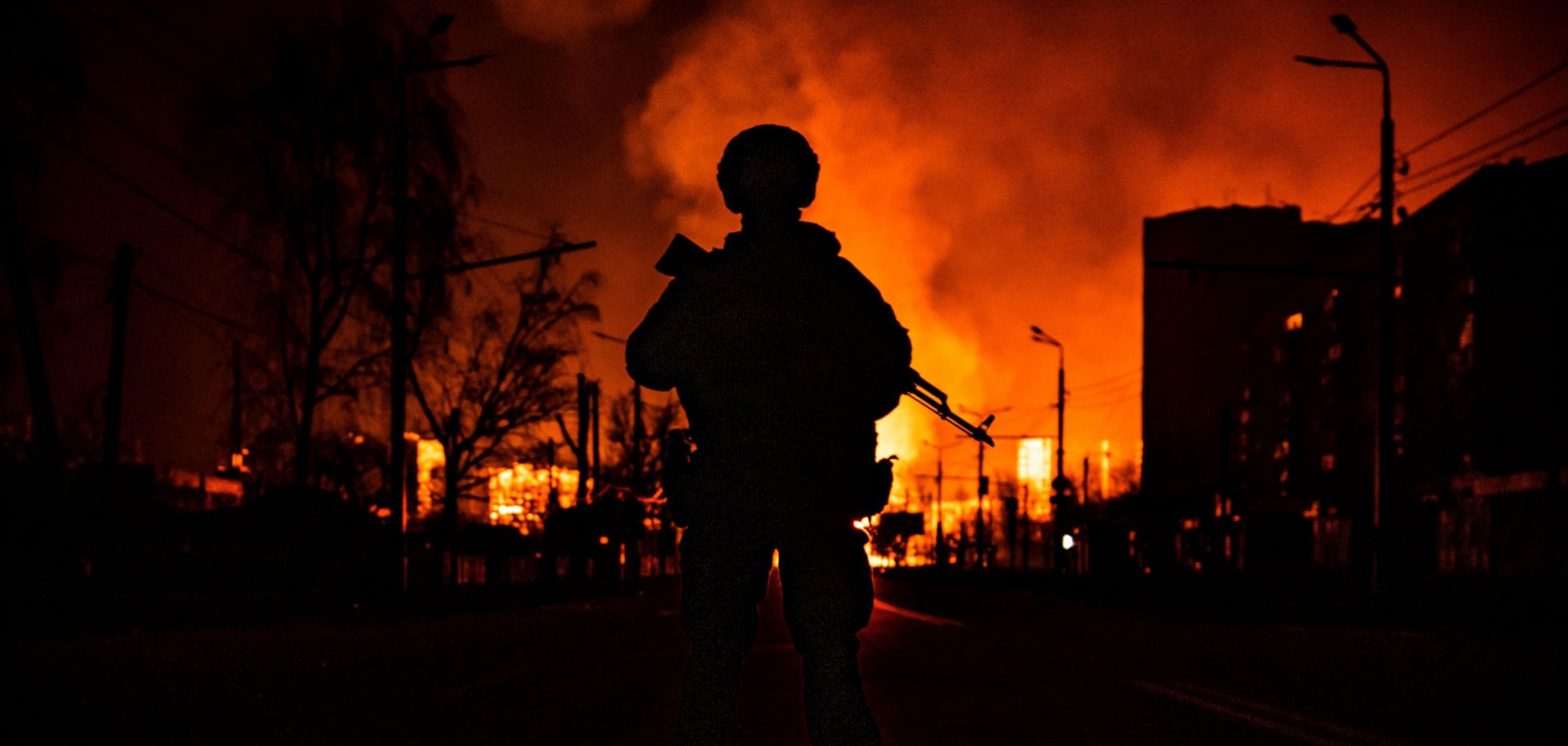 A Ukrainian soldier’s silhouette is seen in the city of Kharkiv on March 30, 2022, as a gas station burns behind him after Russian attacks.