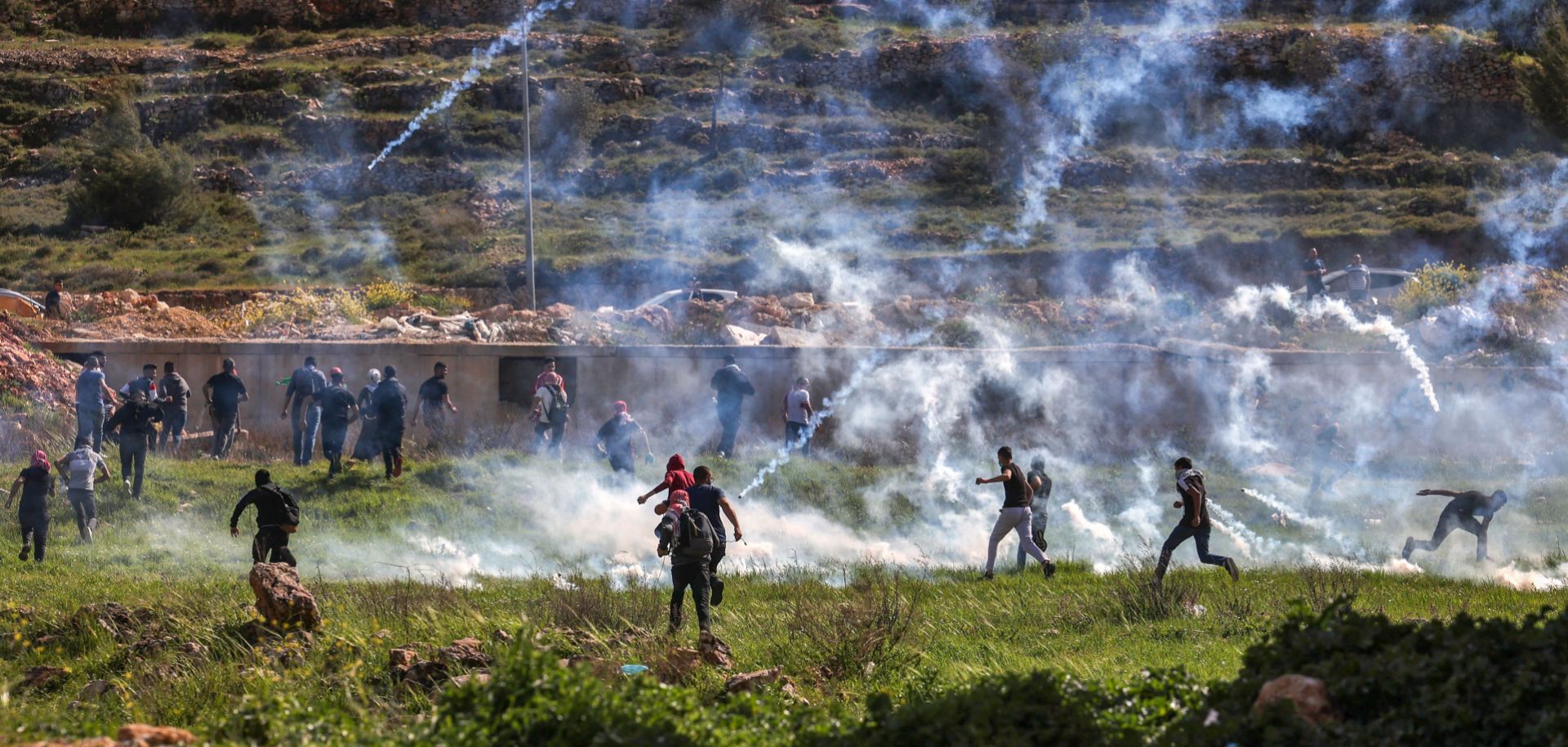 Palestinians run for cover during clashes with Israeli security forces near the Israeli settlement of Beit El in the occupied West Bank on April 11, 2022. 