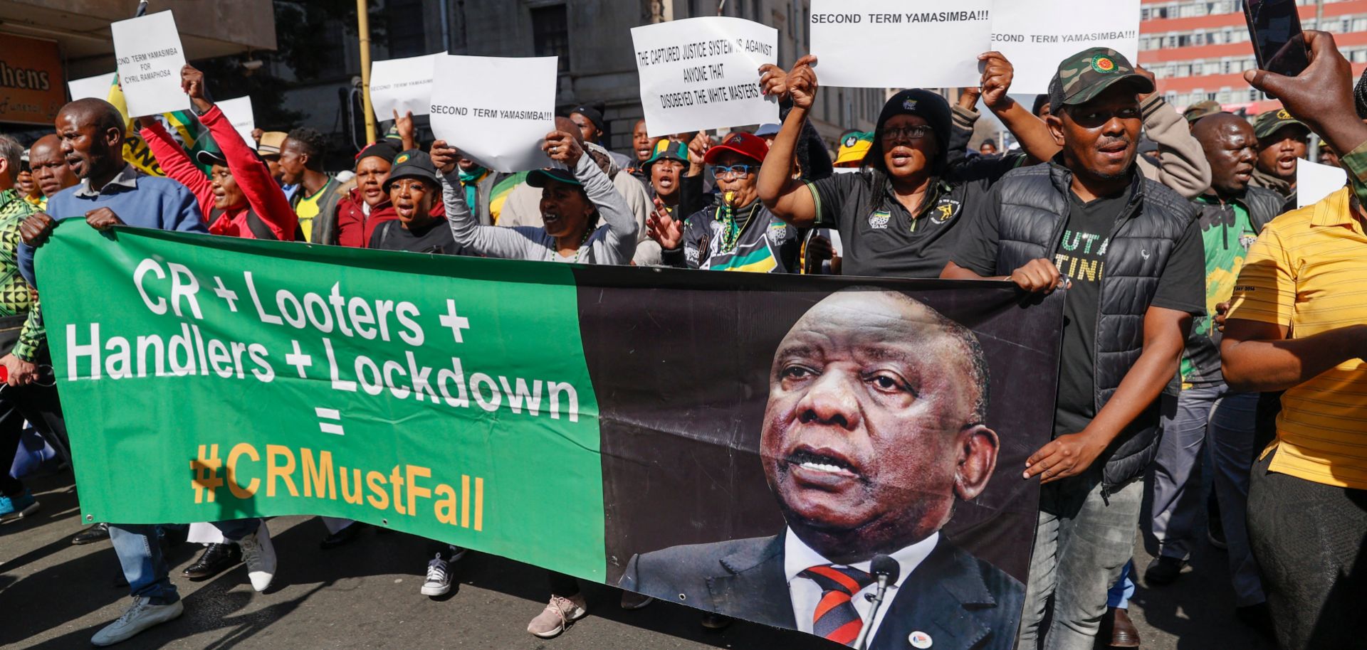 Disgruntled members of South Africa’s ruling African National Congress (ANC) party march to the party’s headquarters in Johannesburg, holding a poster reflecting the face of South African President Cyril Ramaphosa, on July 15, 2022.