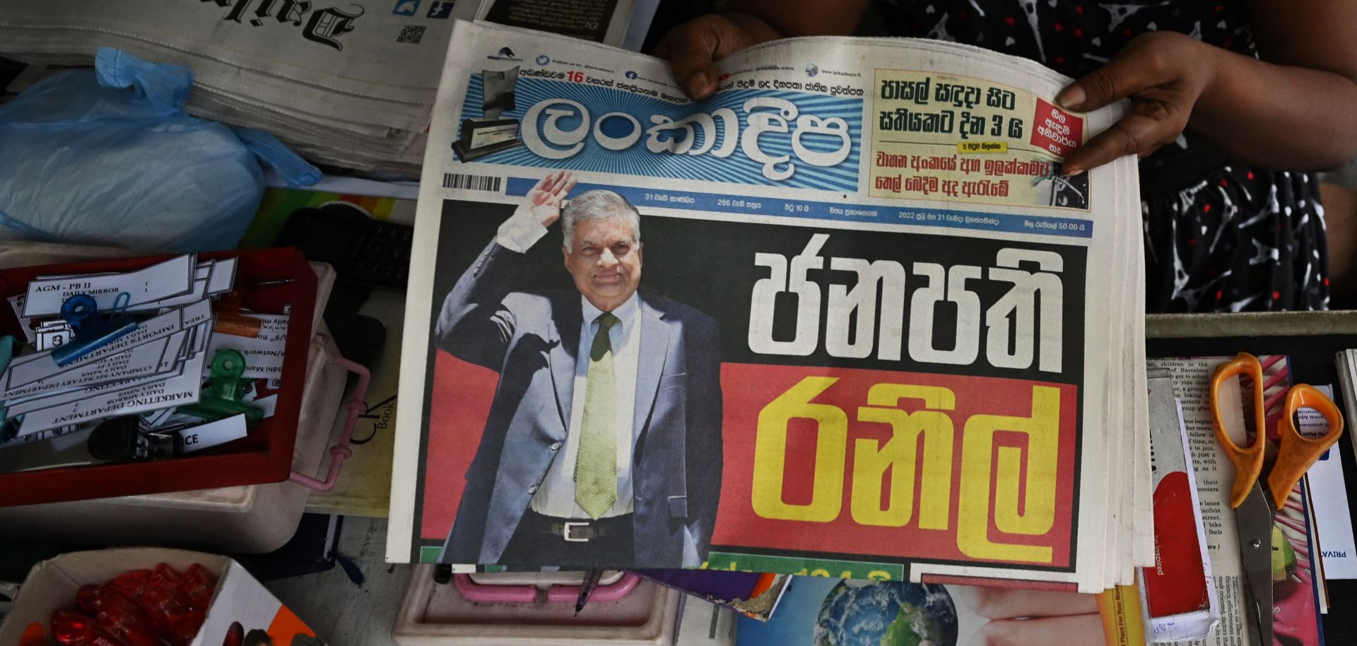 A vendor holds a newspaper with Sri Lanka's President-elect Ranil Wickramasinghe on the front page at a newsstand in Colombo on July 21, 2022. The six-time prime minister was sworn in as president later that day.