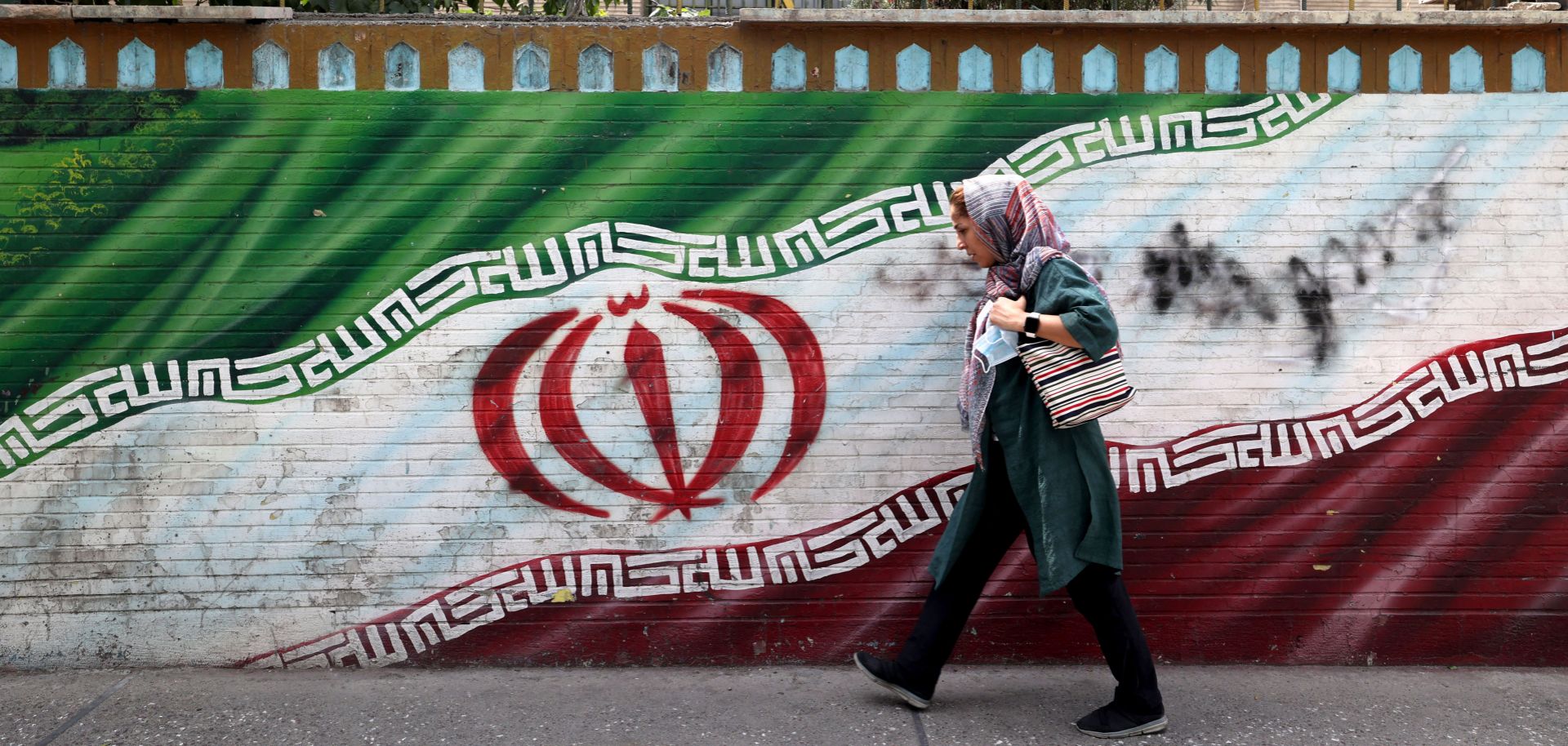 A woman walks past a mural in Tehran, Iran, on July 31, 2022.