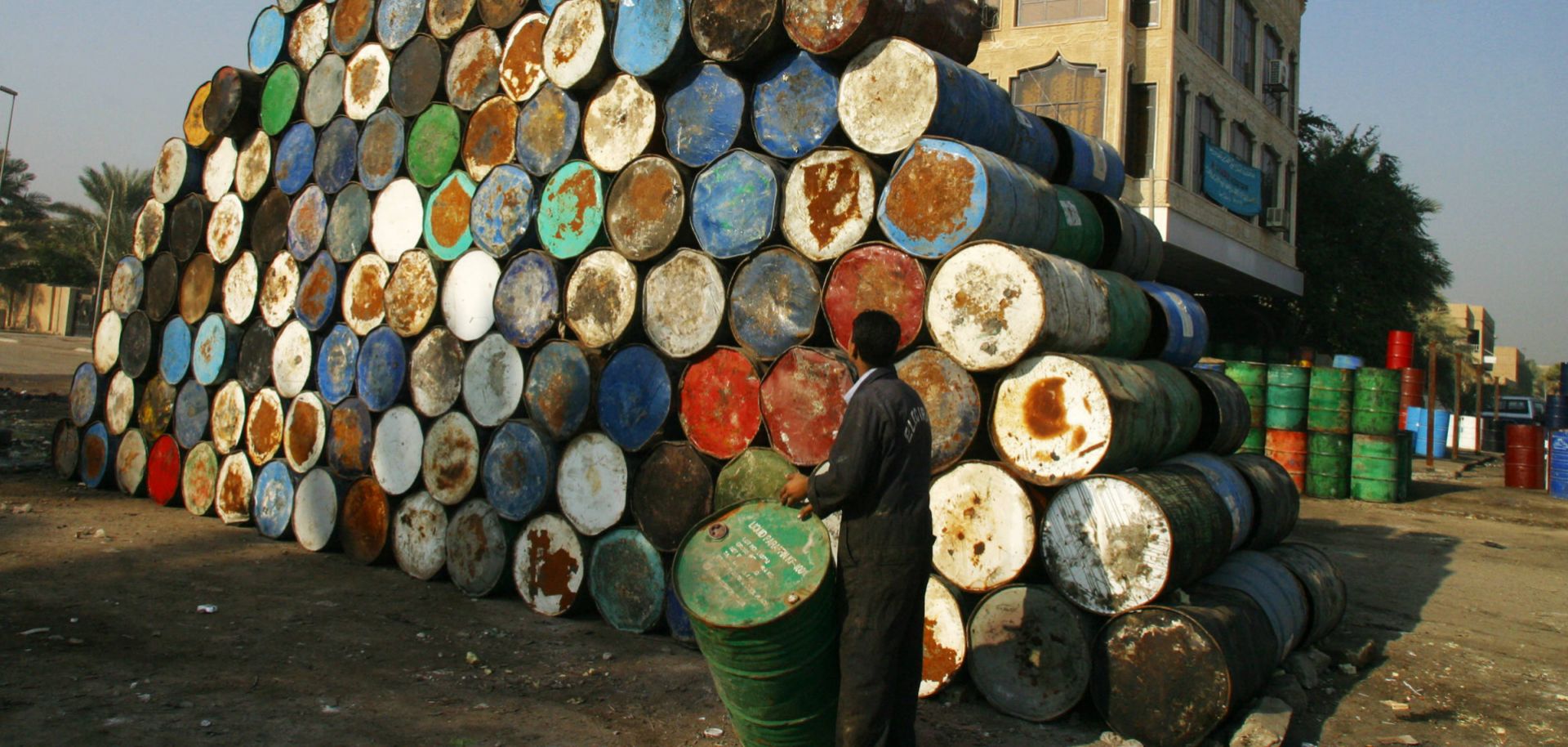 A worker surveys a stack of empty oil drums as he brings another to add to it at a warehouse in Baghdad, Iraq, on Jan. 6, 2004.