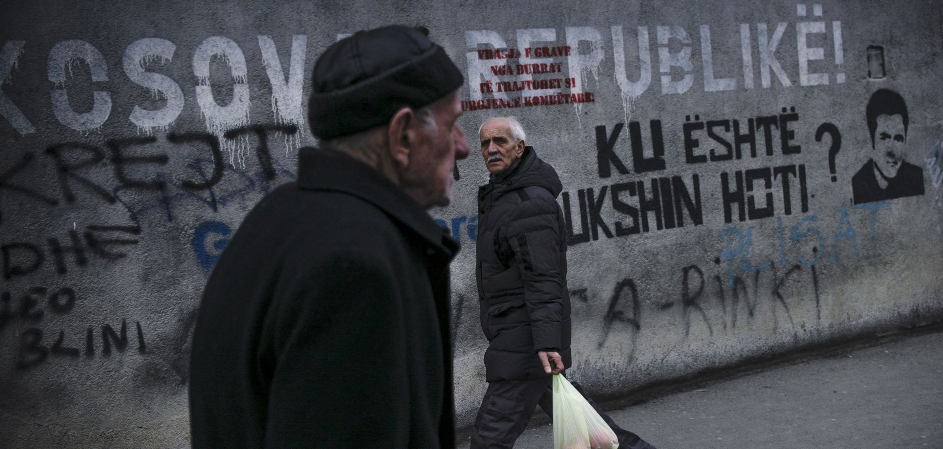 People walk past a mural reading ''Republic of Kosova'' in Pristina on Feb. 27, 2023, as the European Union hosts talks between the rival leaders of Kosovo and Serbia.