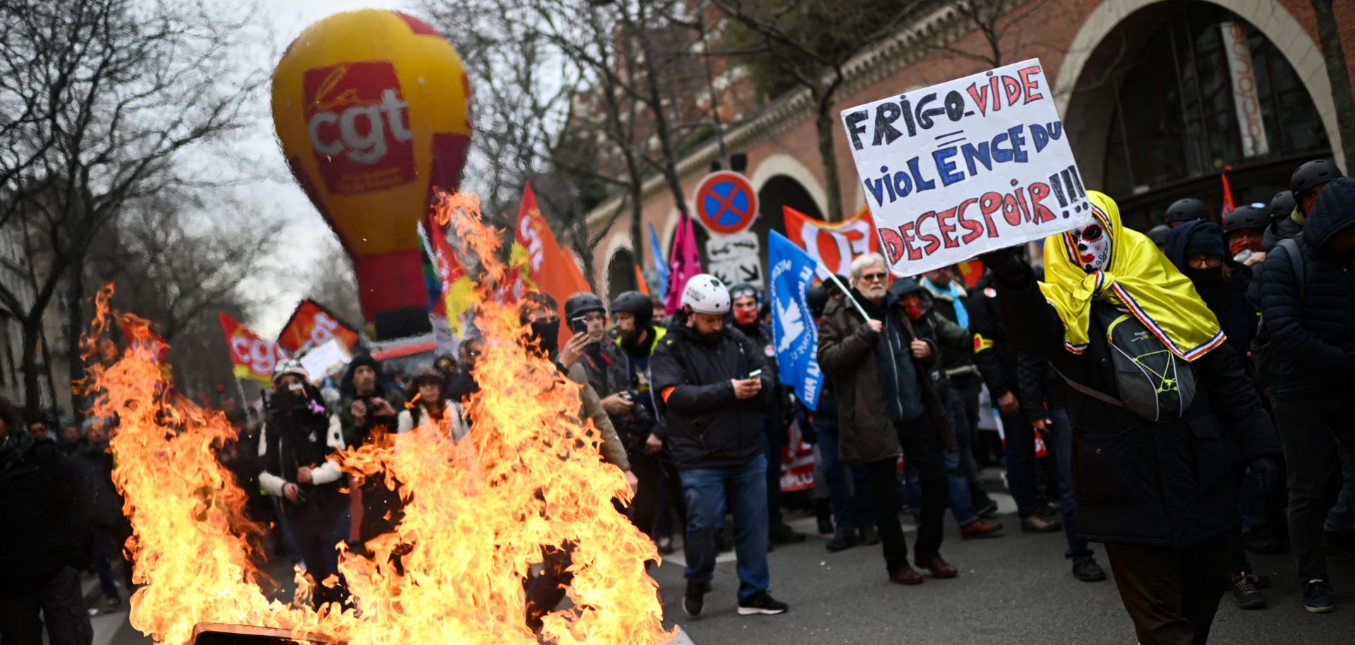 A protestor holds a placard that reads ''Empty Fridge Equals Violence of Dispair'' near a pile of burning trash during a demonstration in Paris, France, against the government's proposed pension reform on March 11, 2023. 