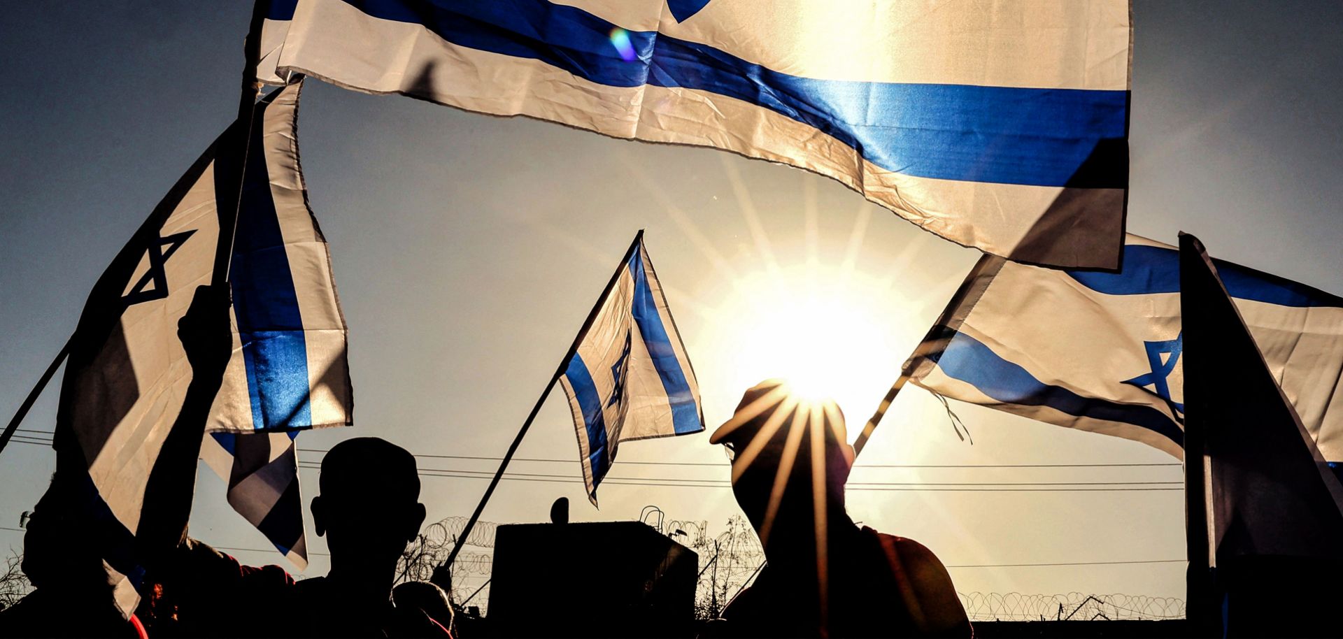 Israeli military veterans wave national flags during a rally against the government's judicial reform bill along a highway near Netanya on March 28, 2023.