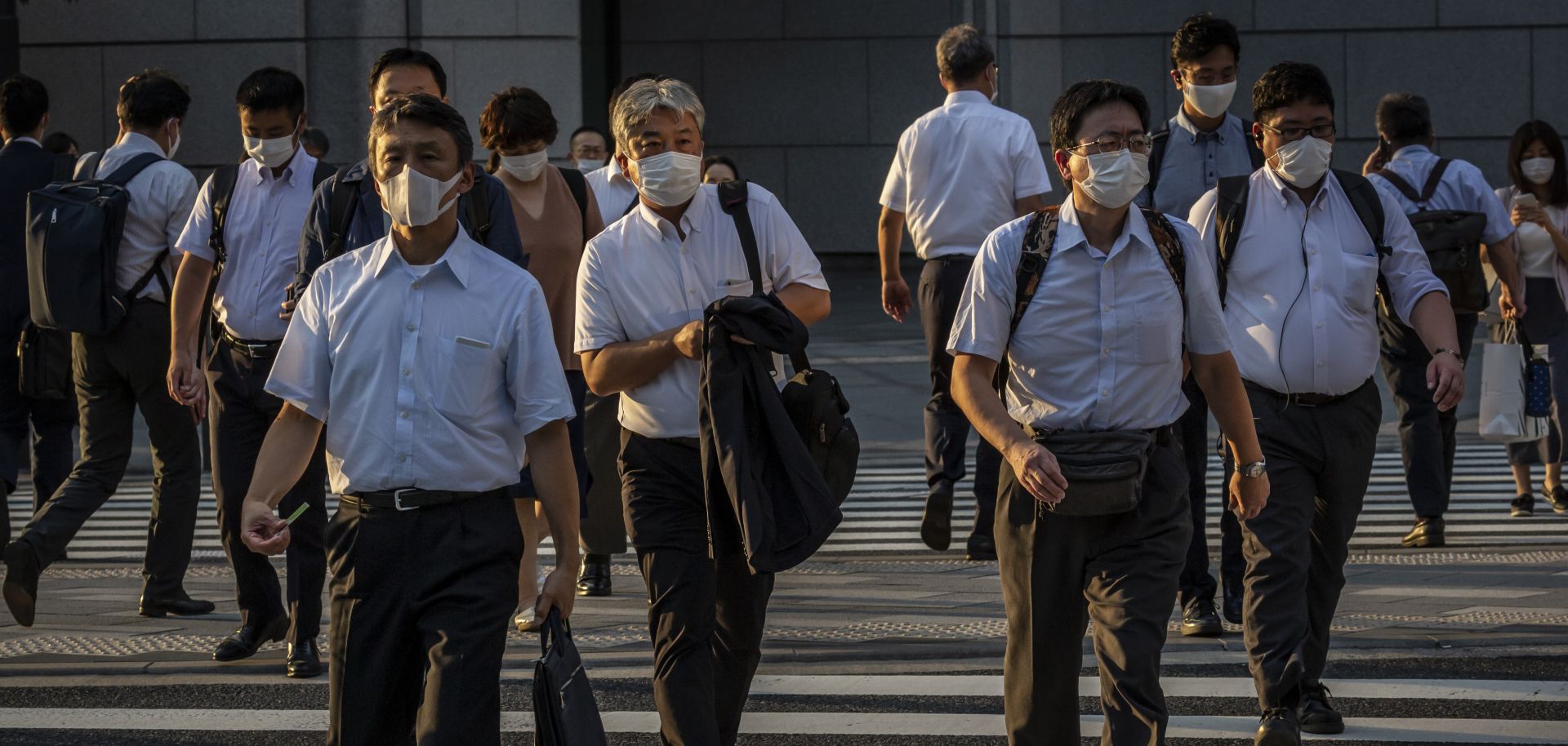 People wearing face masks cross a street on July 28, 2021, in Tokyo, Japan. 