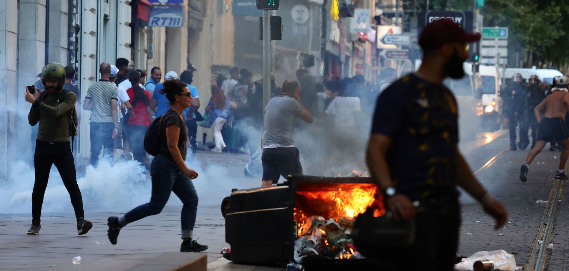 Protesters run from launched tear gas canisters during clashes with police in Marseille, southern France, on July 1, 2023, after a fourth consecutive night of rioting over the killing of a teenager by police.