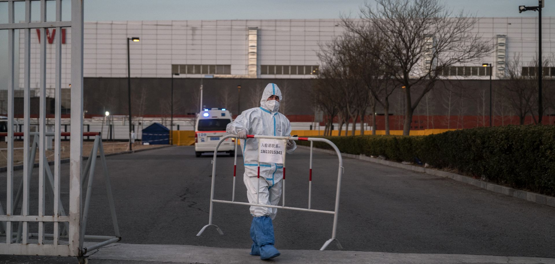 A worker places a barricade on a road after allowing an ambulance to enter a COVID-19 quarantine facility in Beijing, China, on Dec. 7, 2022. 