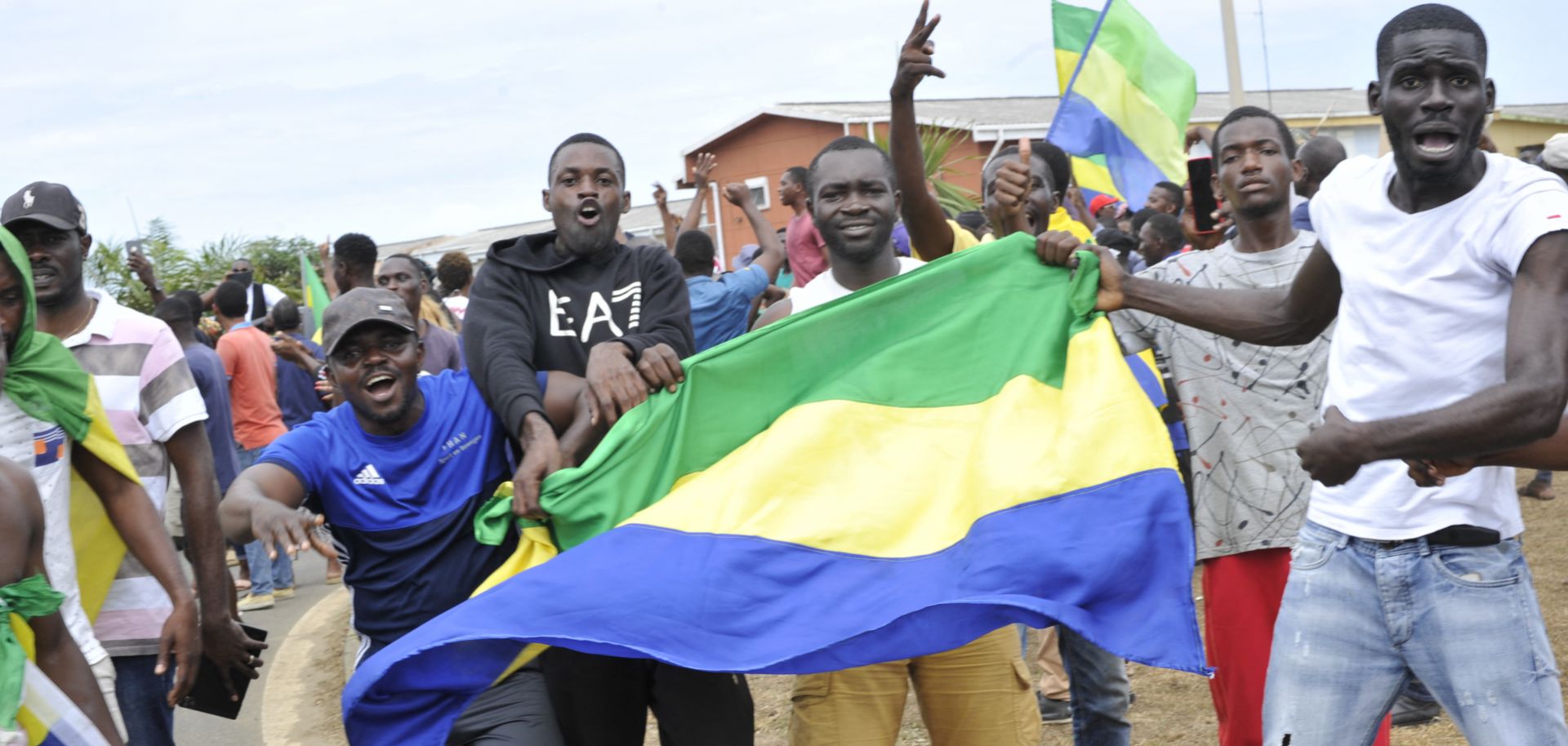 People hold up Gabon's national flag in the country's capital of Libreville on Aug. 30, 2023, as they celebrate after a group of military officers announced they were ''putting an end to the current regime'' and scrapping official election results that had handed another term to President Ali Bongo Ondimba. 