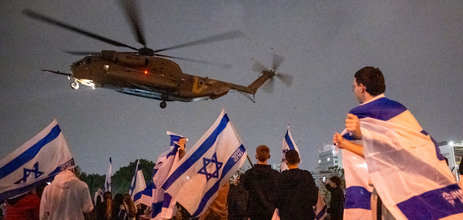 People wave flags and cheer as a helicopter with Israeli hostages released earlier by Hamas lands at a medical center on Nov. 26, 2023, in Petah Tikva, Israel.