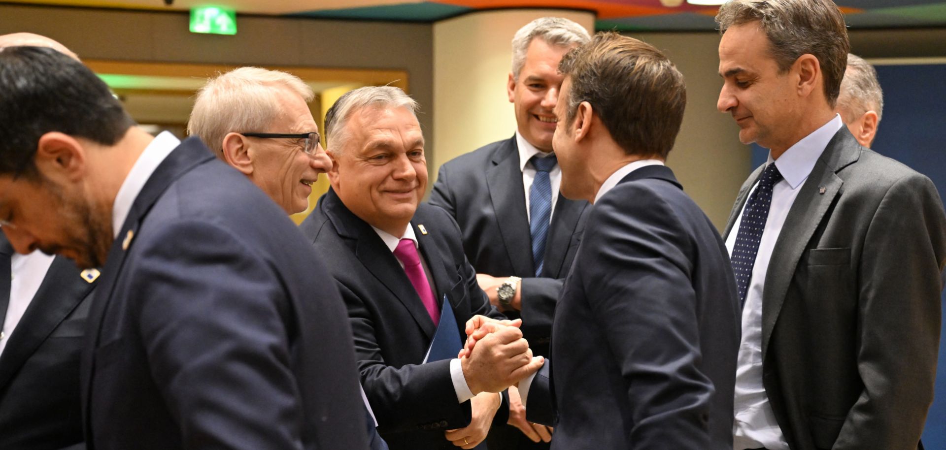 Hungarian Prime Minister Viktor Orban (center left) and French President Emmanuel Macron (center right) shake hands ahead of an EU summit in Brussels, Belgium, on Dec. 14, 2023. 